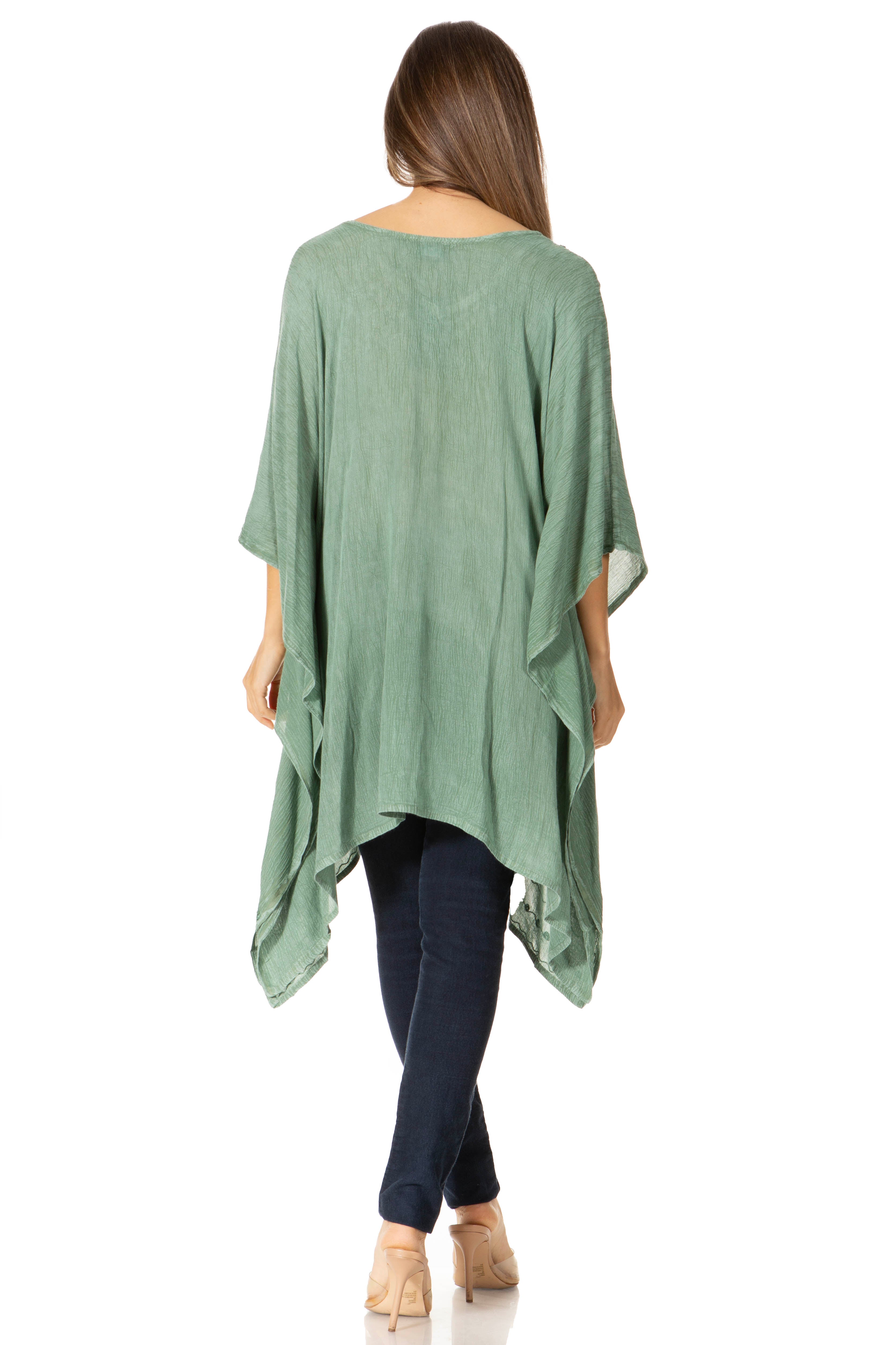 Woman wearing a green poncho over a dark outfit on a white background