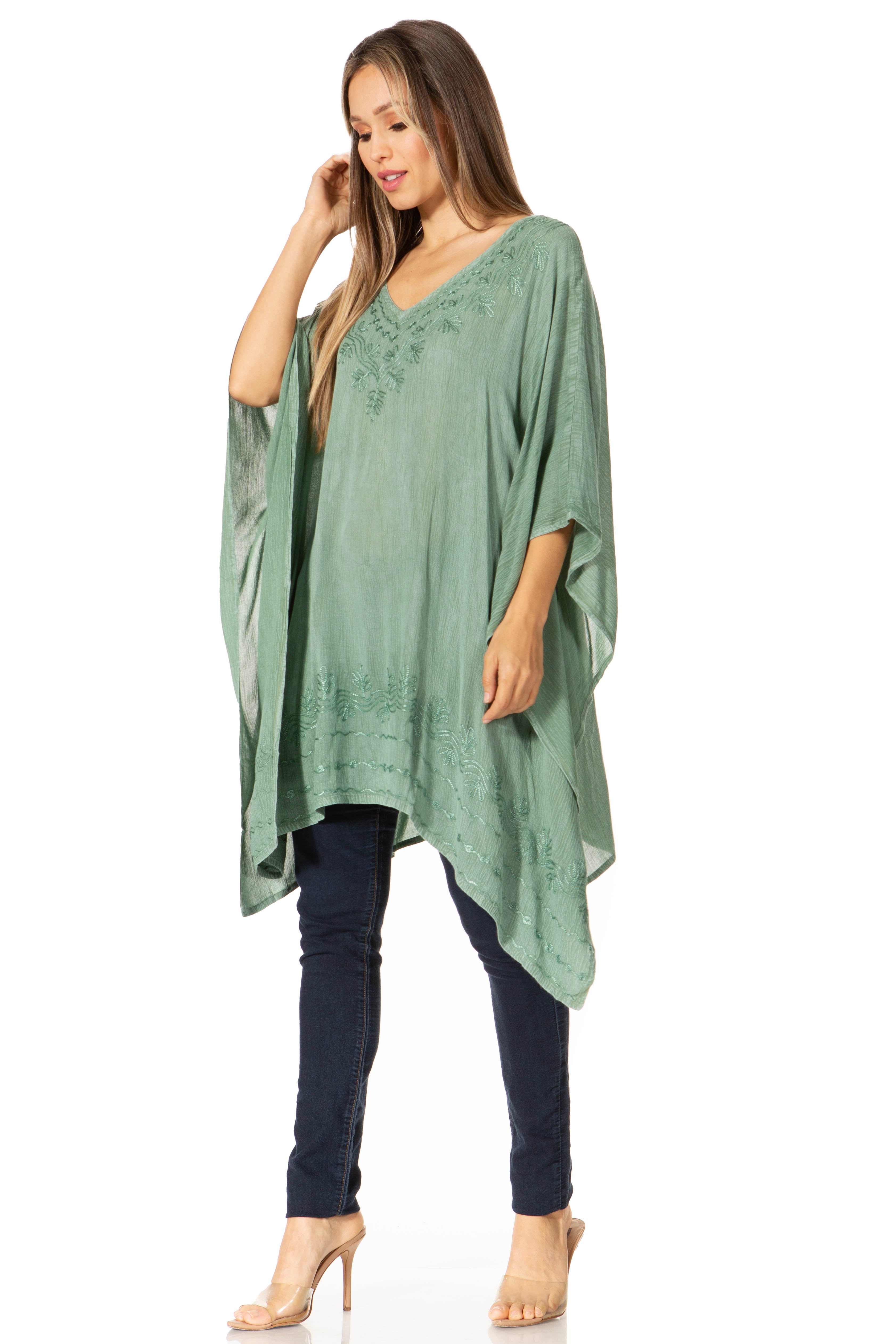 Woman wearing a green poncho over a blue top and jeans on a white background