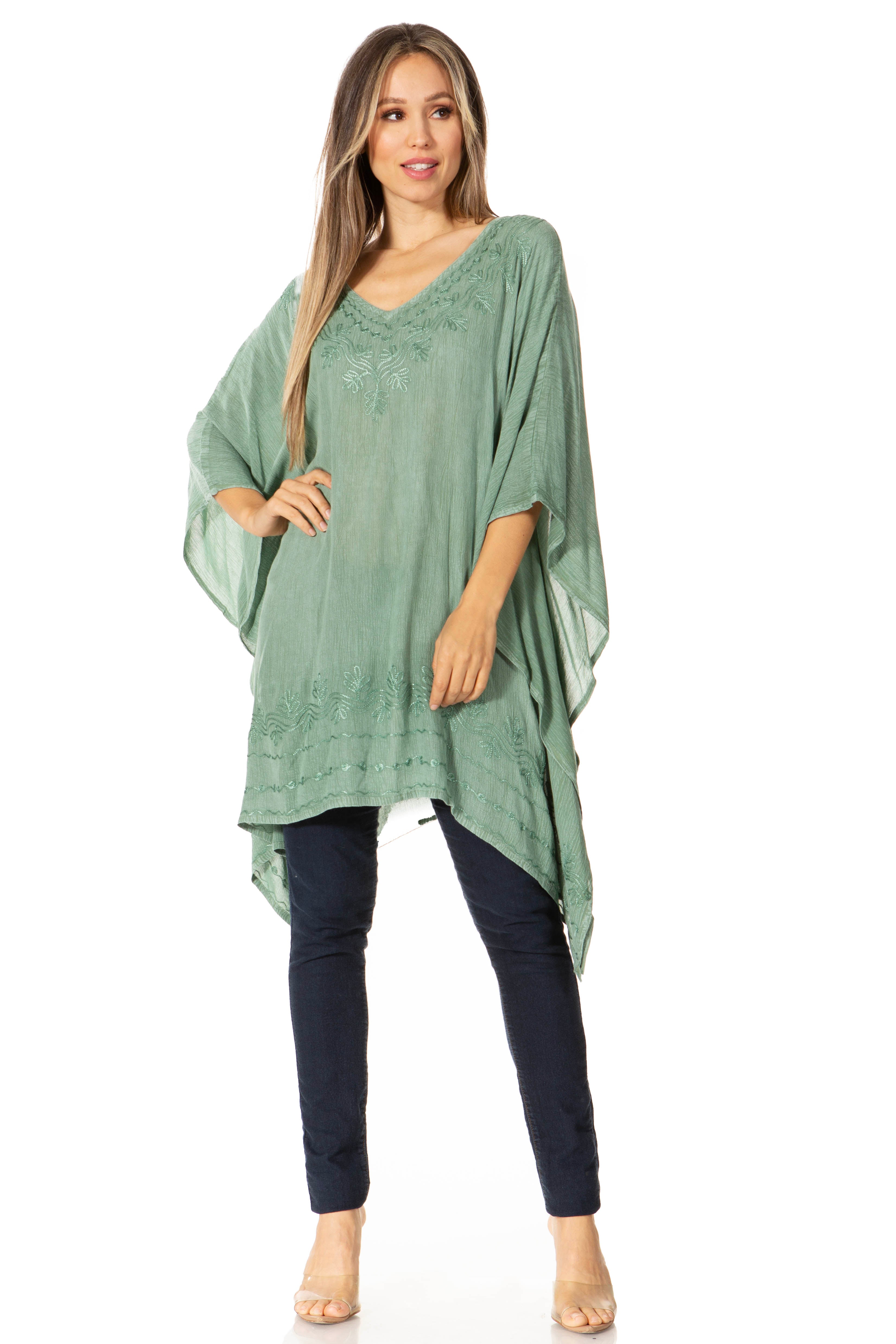 Woman wearing a green poncho over a black top and pants on a white background