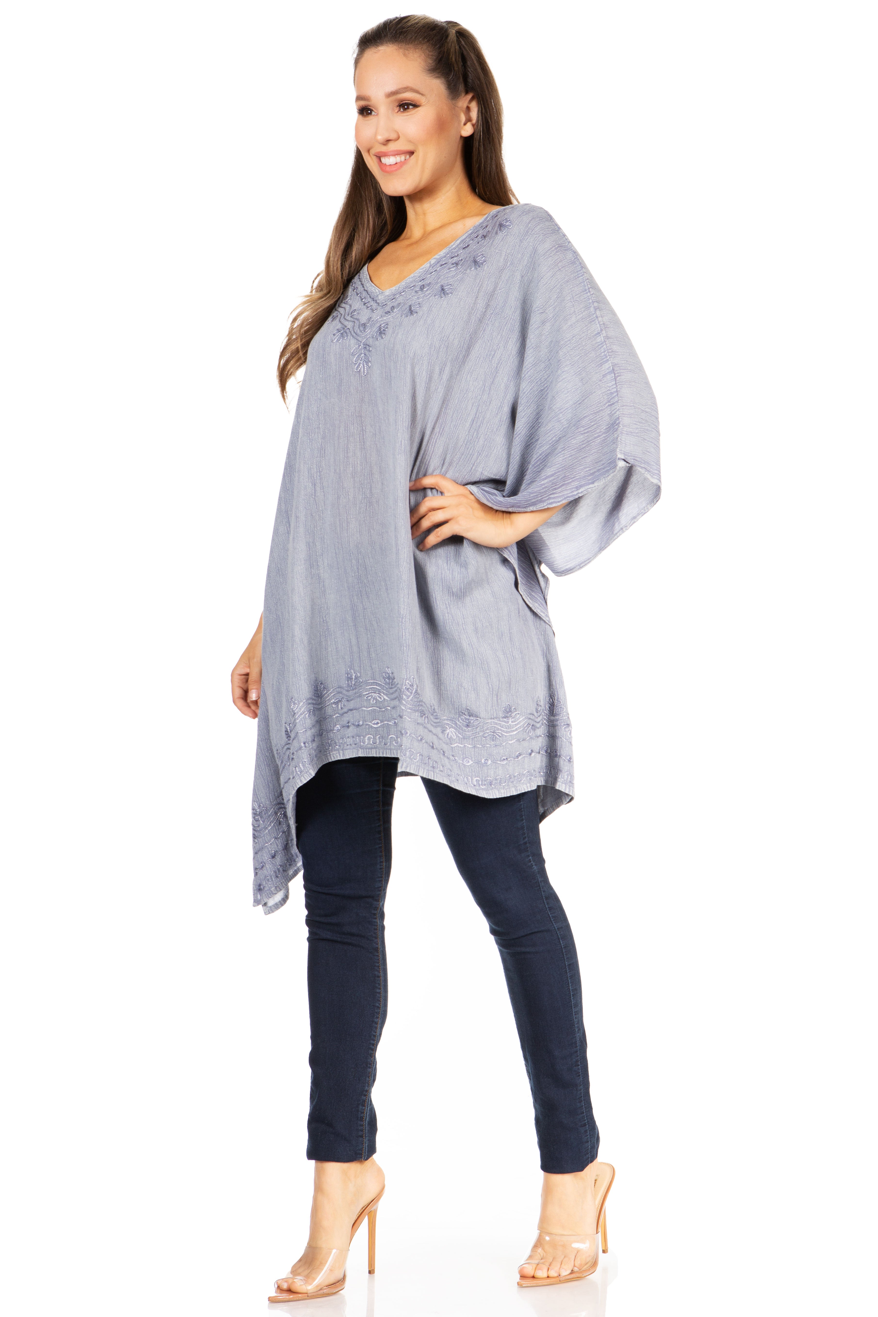 Woman wearing a light gray poncho over a dark blue outfit on a white background