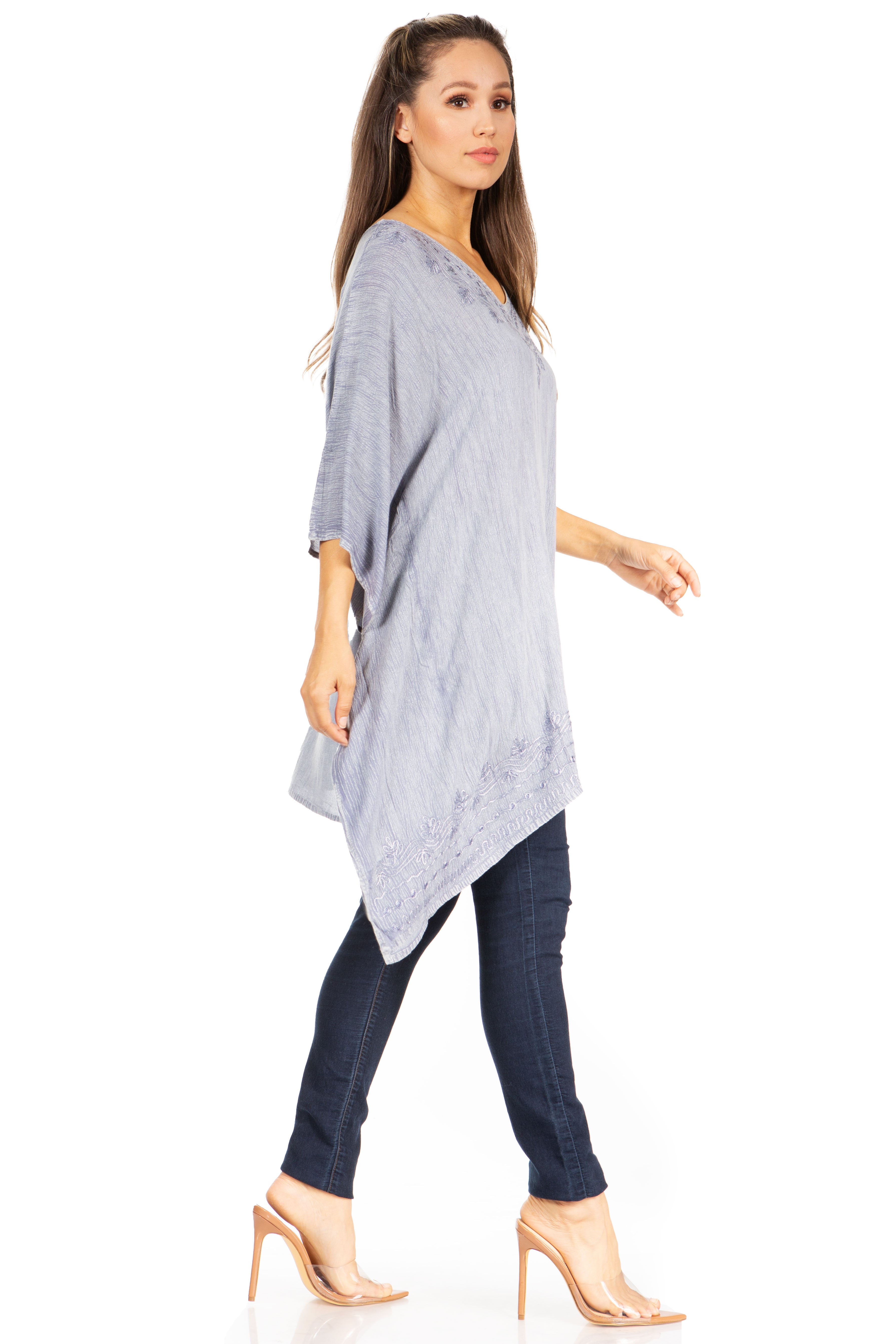 Woman wearing a gray poncho and dark pants on a white background