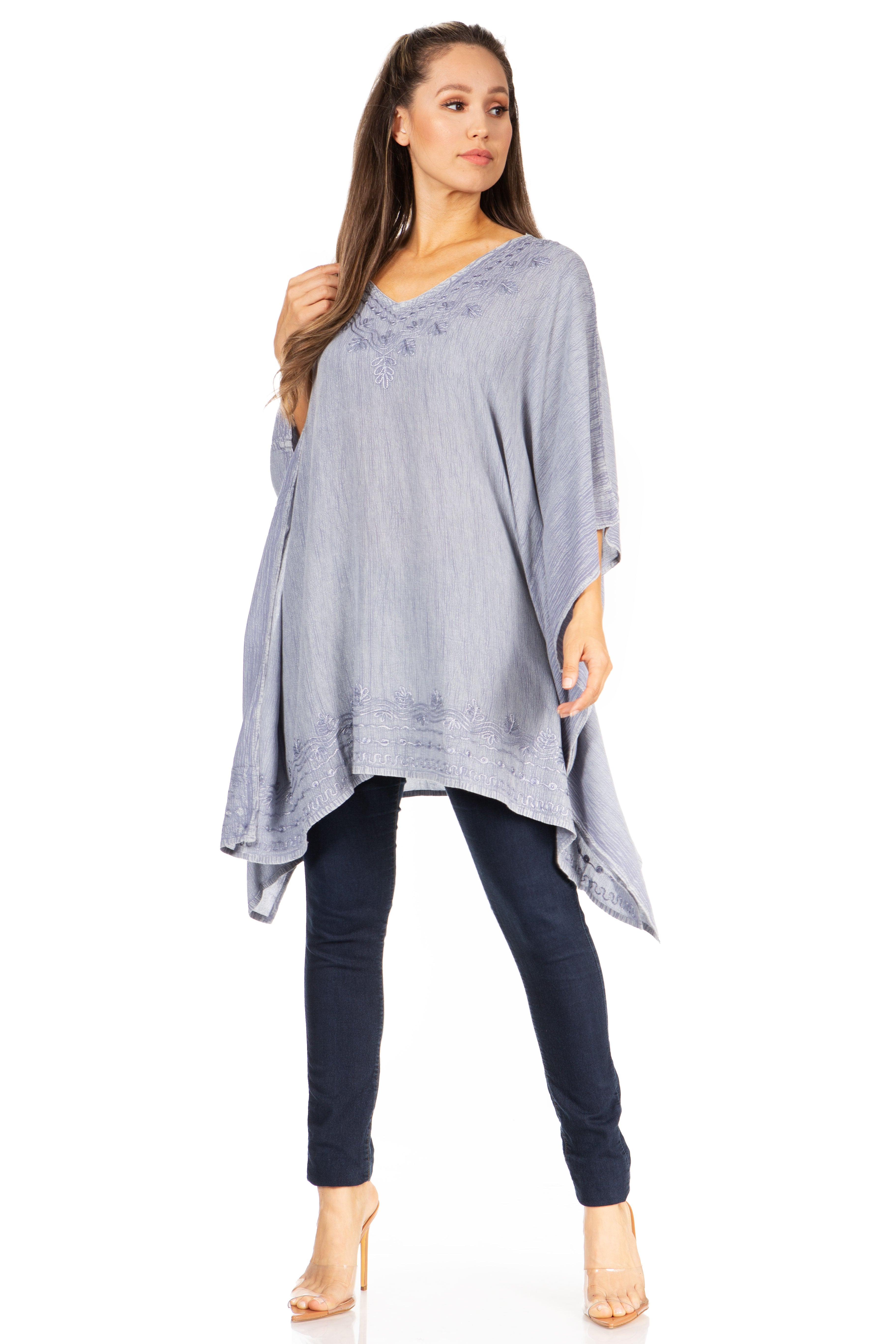 Woman wearing a light blue poncho over a dark outfit on a white background