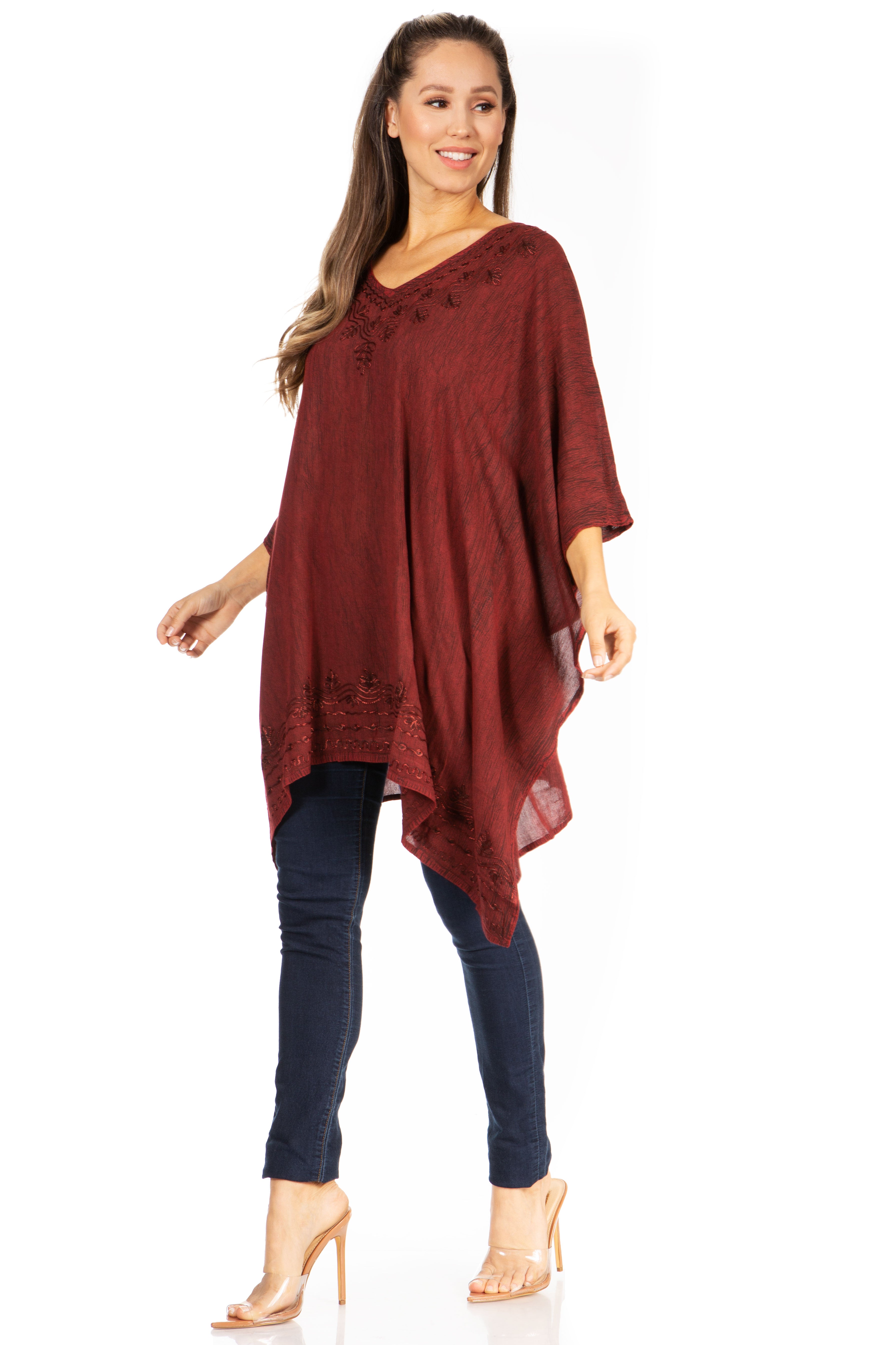 Woman wearing a burgundy poncho over a navy outfit on a white background