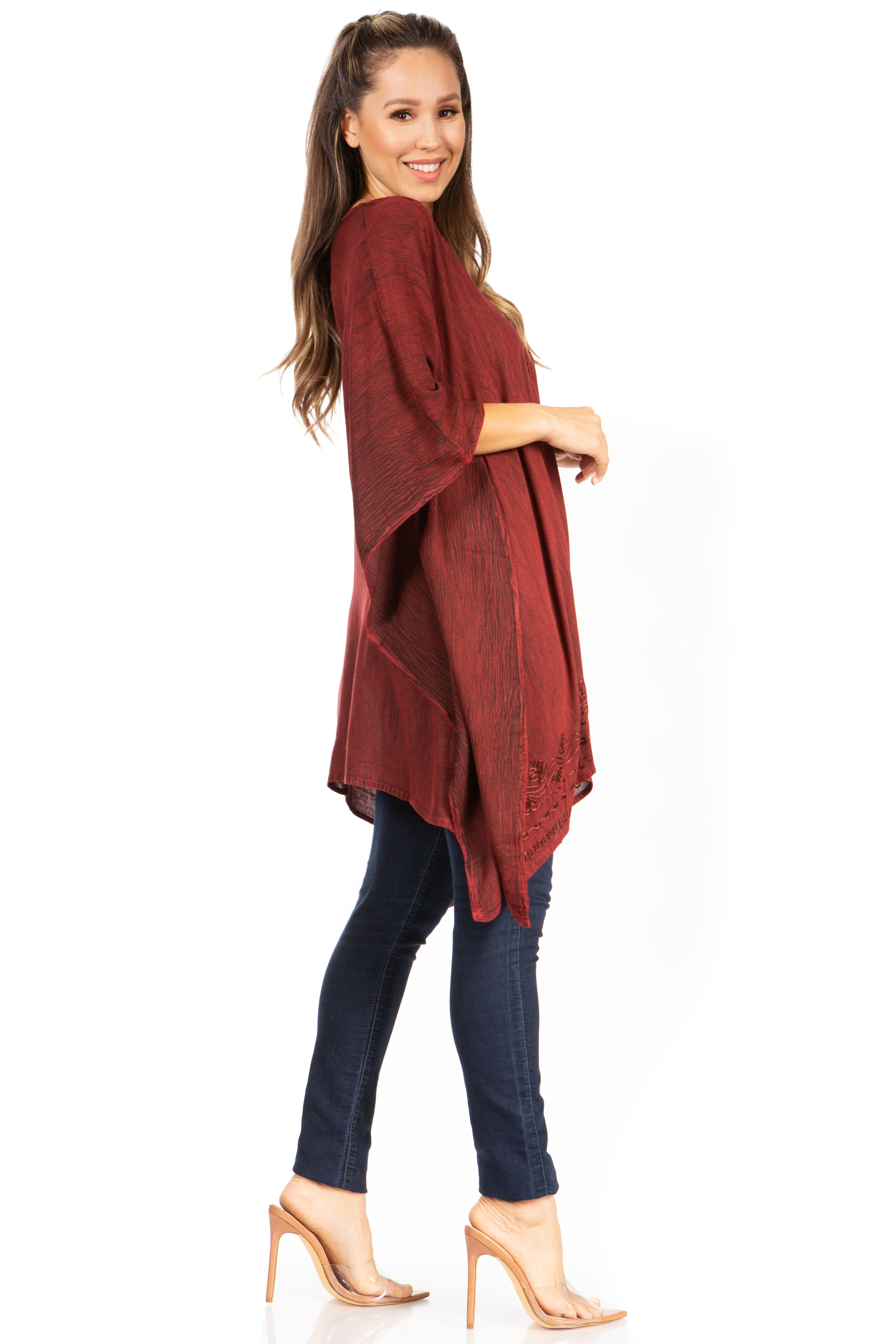 Woman wearing a red poncho and dark jeans on a white background