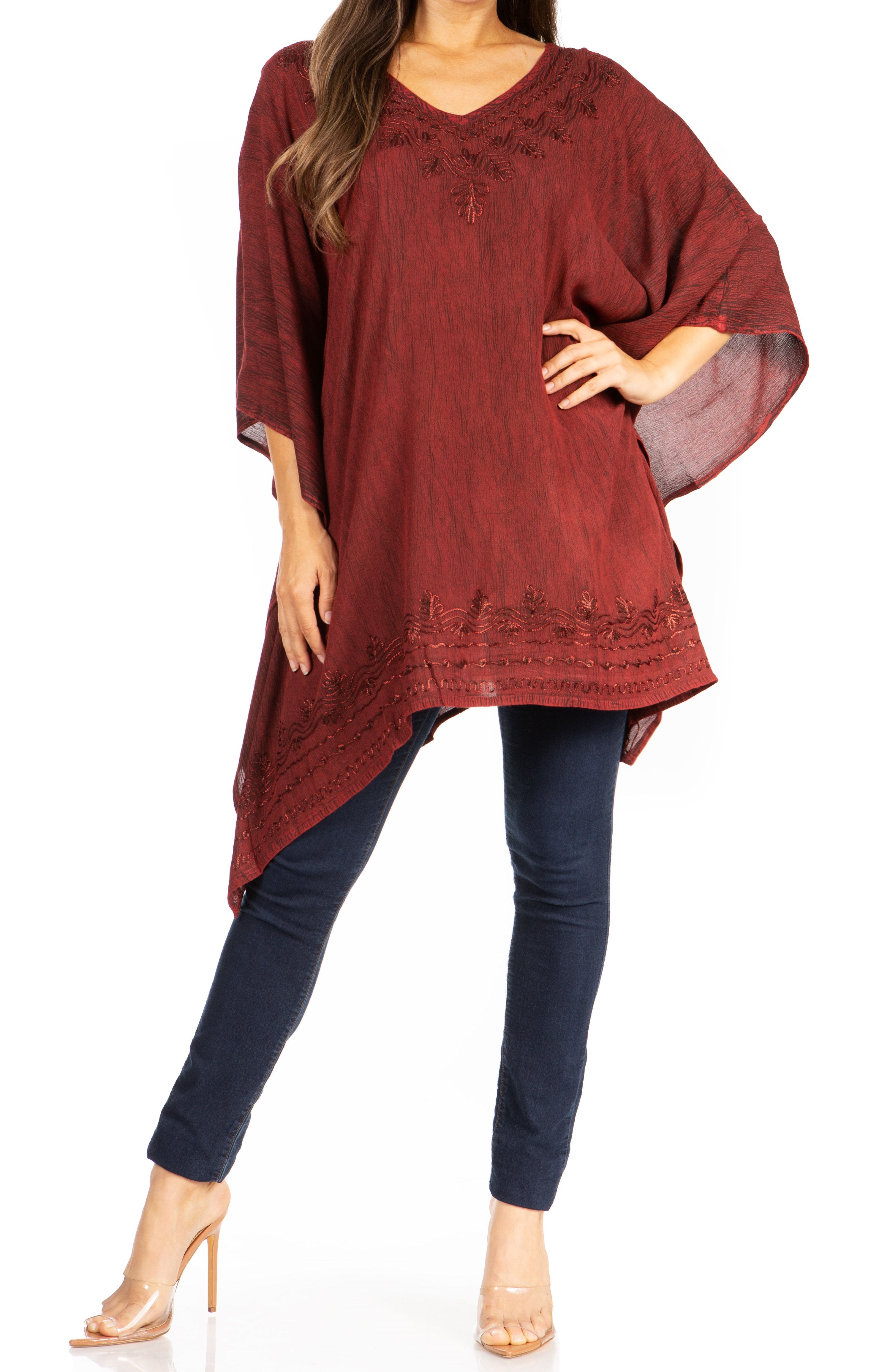 Woman wearing a burgundy embroidered top and dark blue jeans on a white background