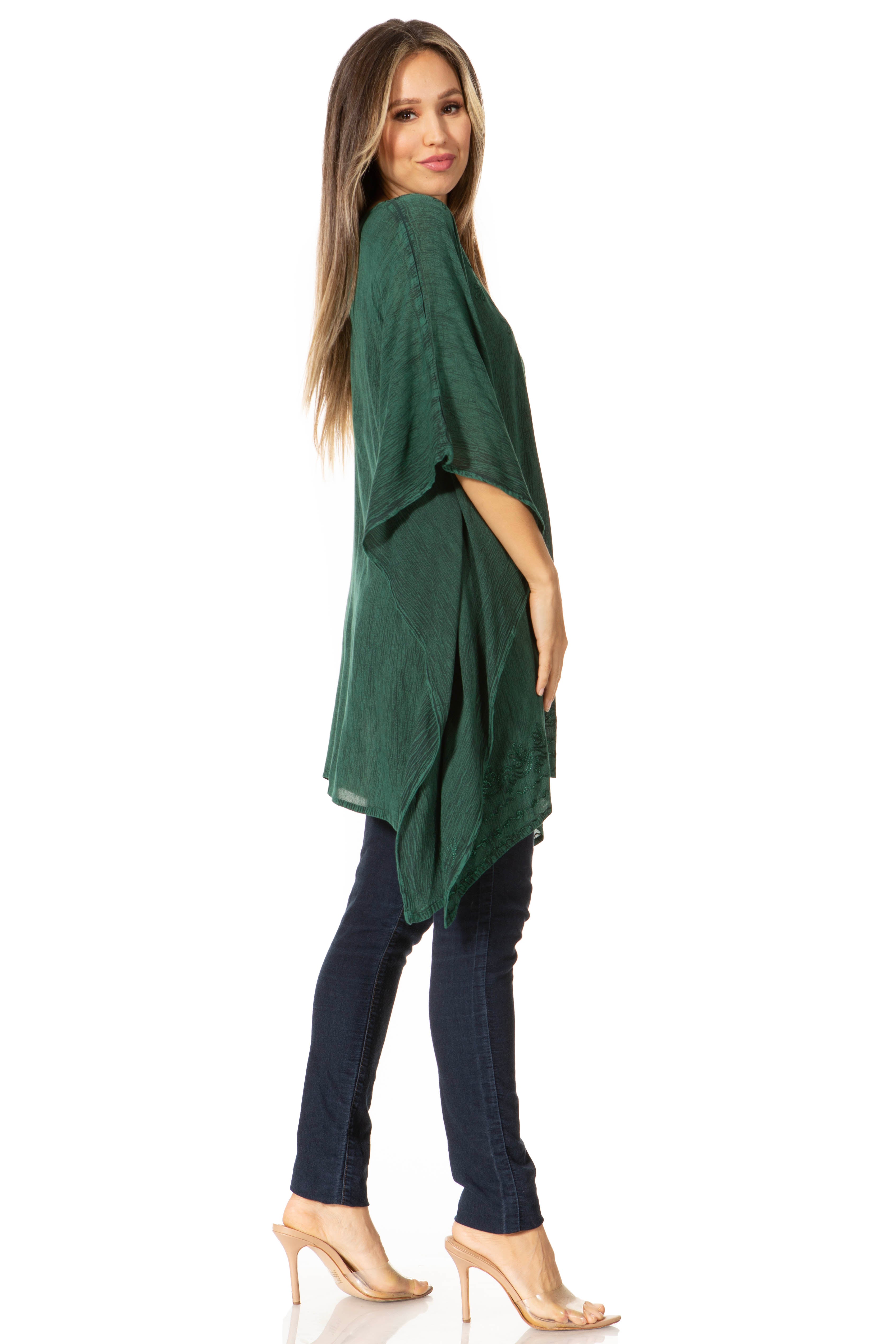 Woman wearing a green poncho and dark blue pants on a white background