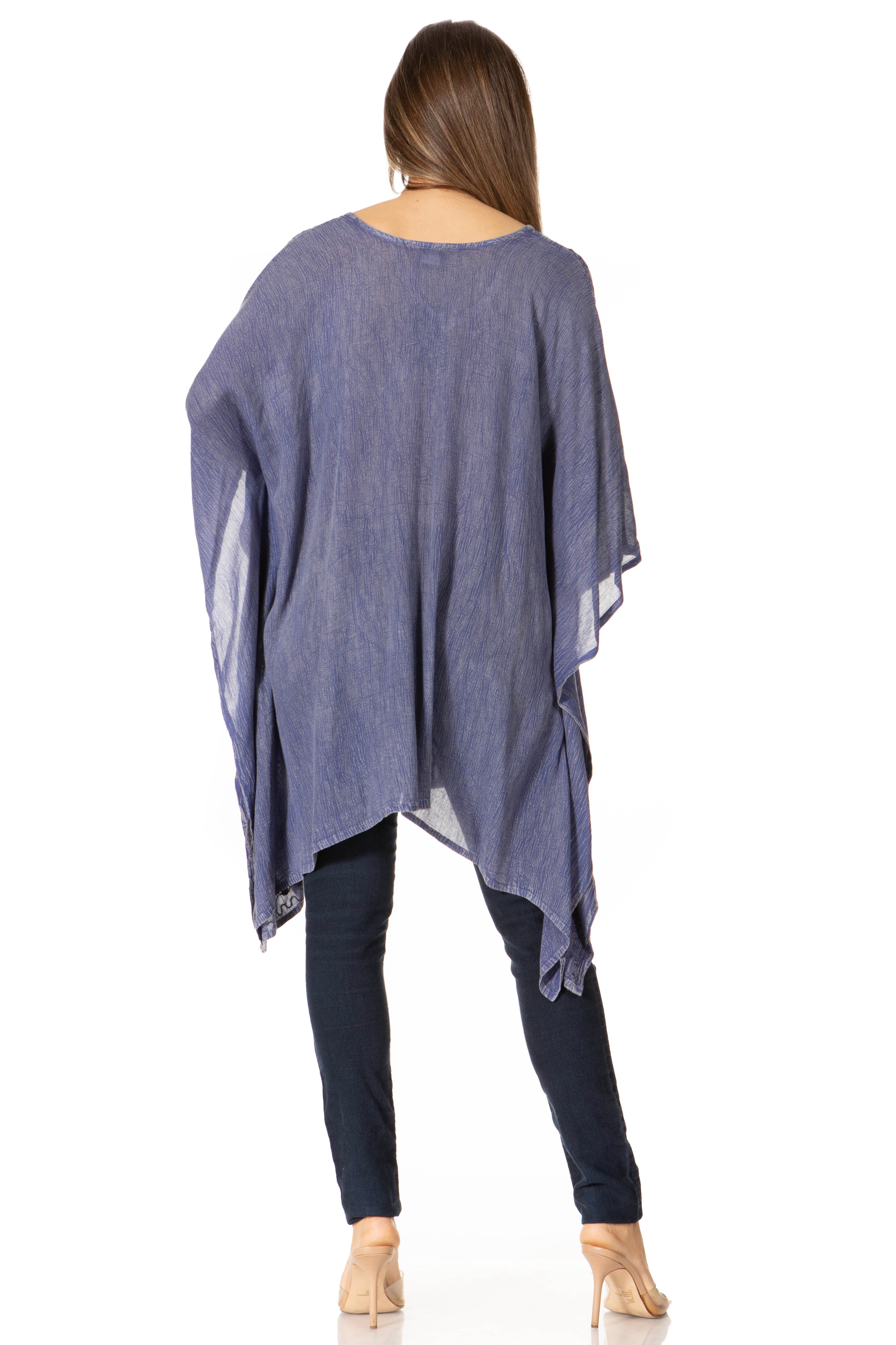Woman wearing a blue poncho over dark pants on a white background