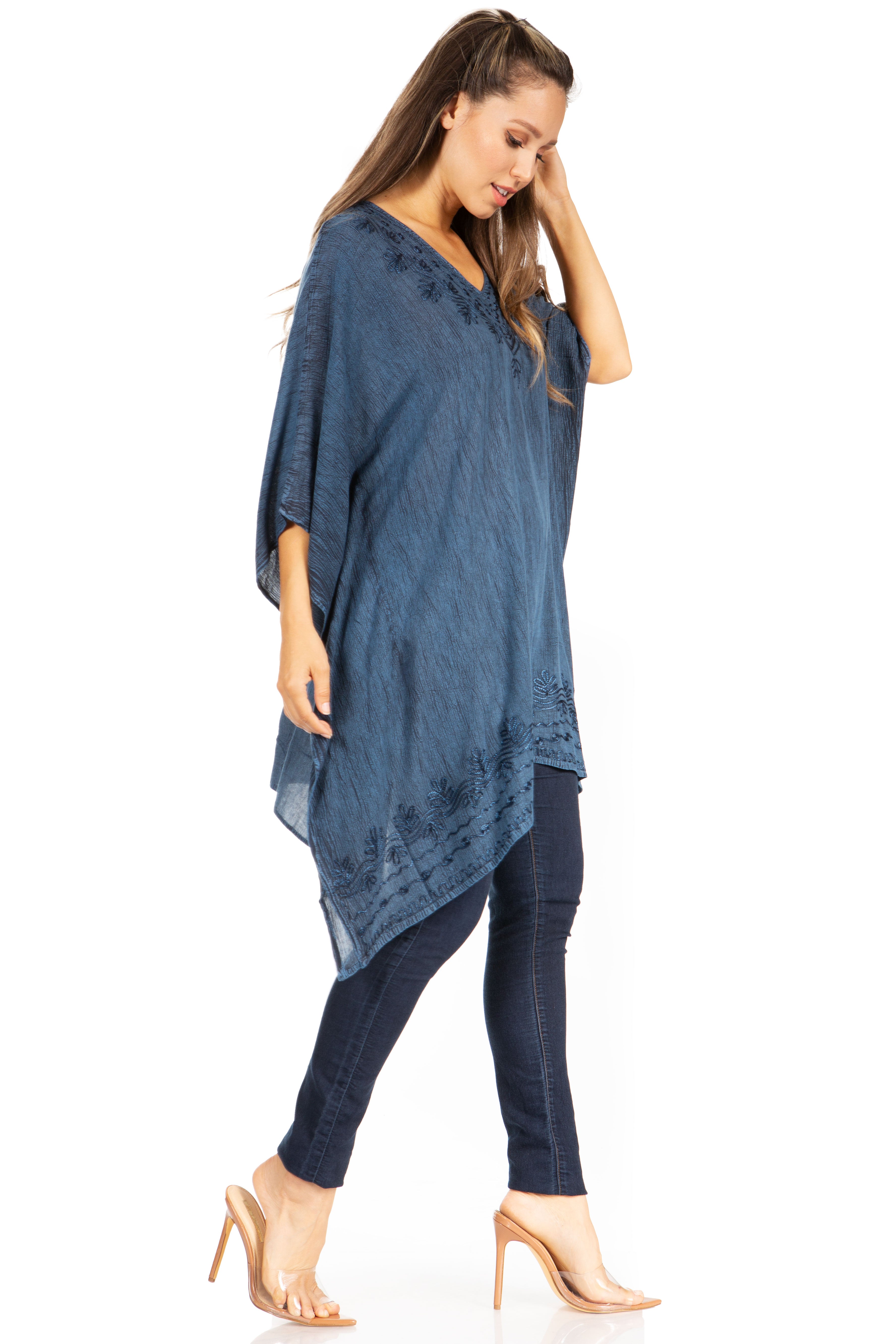 Woman wearing a blue poncho over a matching outfit on a white background