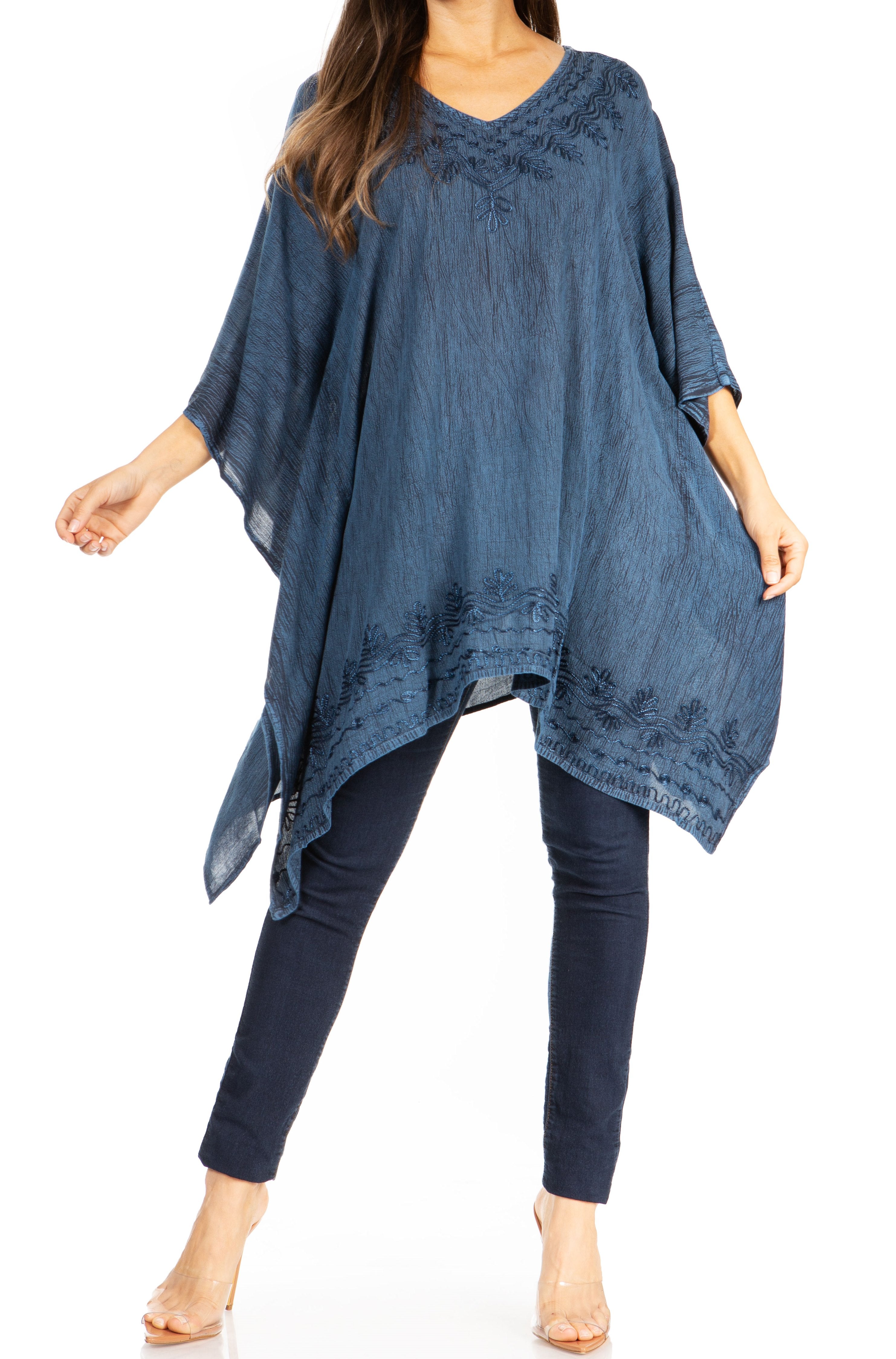 Woman wearing a blue poncho over a dark outfit on a white background
