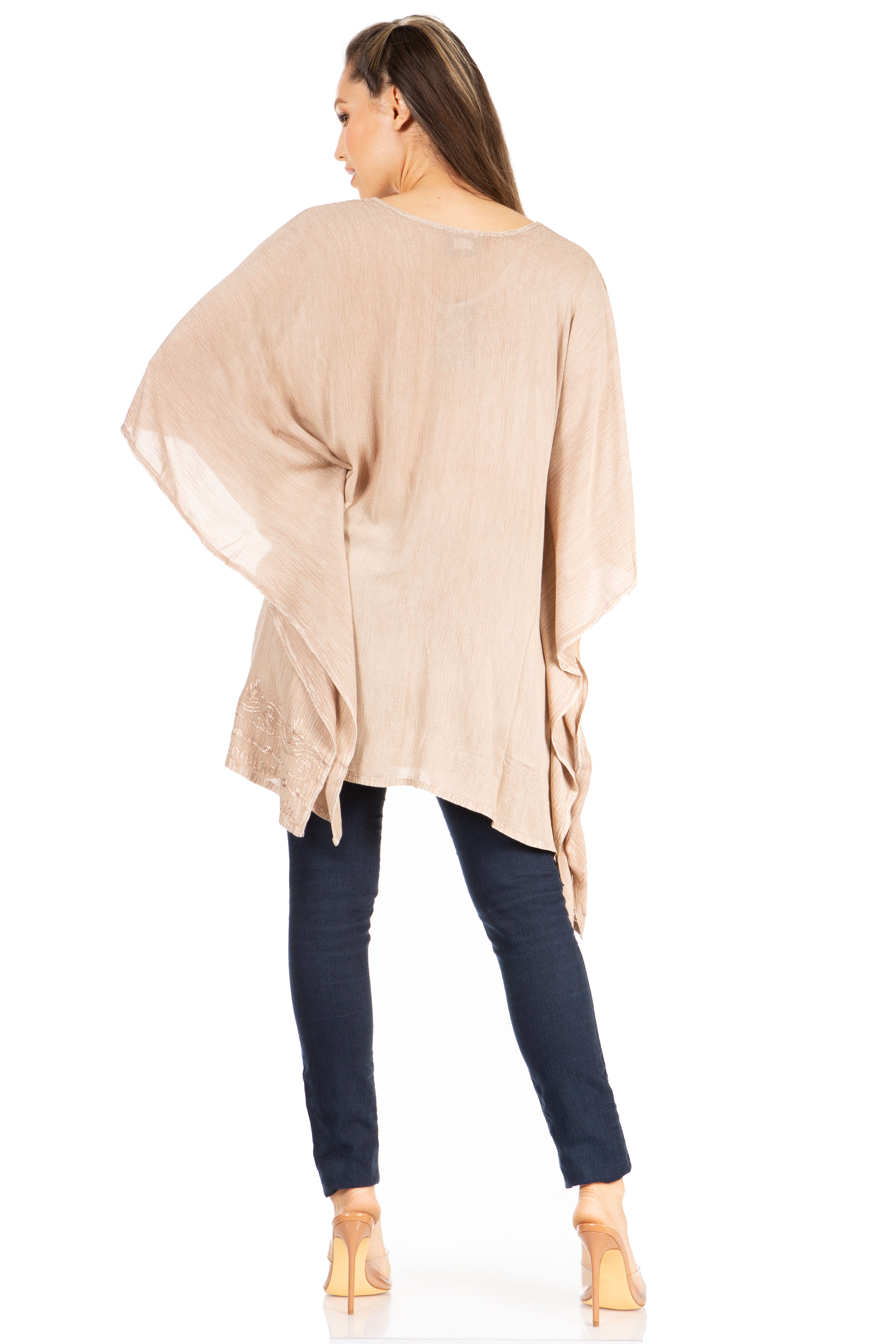 Woman wearing a beige long-sleeve top and dark jeans on a white background