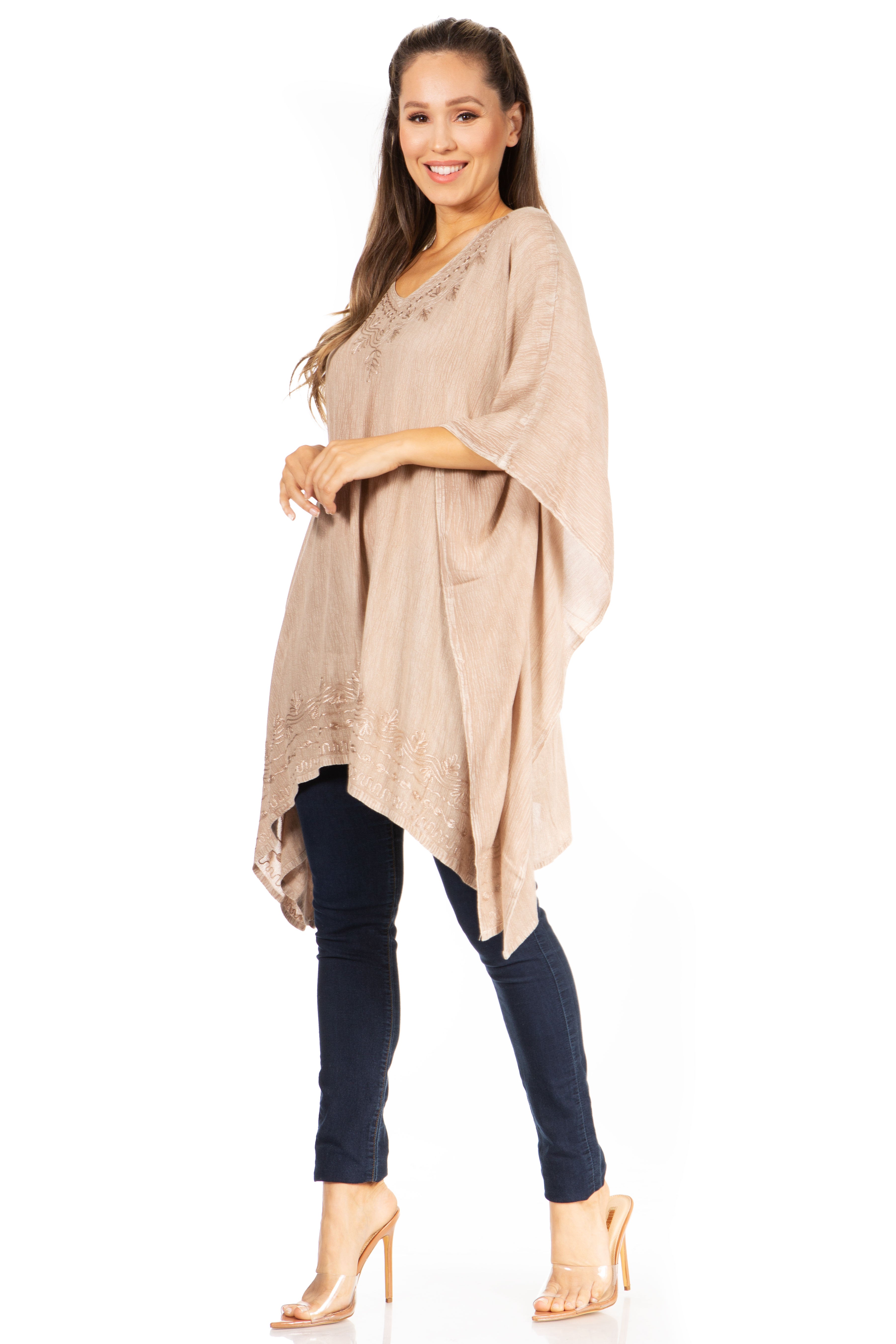 Woman wearing a beige tunic and dark pants on a white background