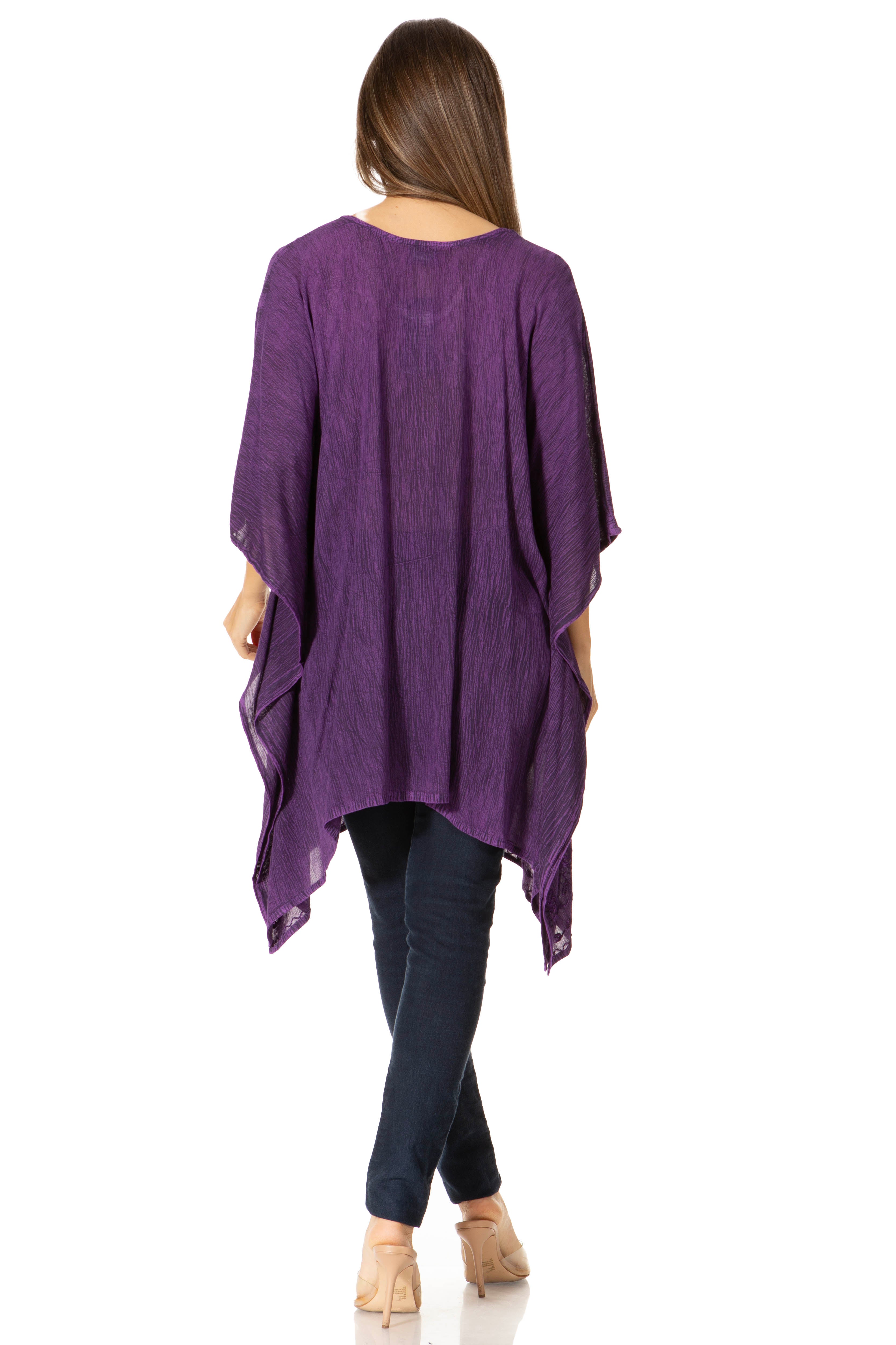 Woman wearing a purple poncho over a dark outfit on a white background