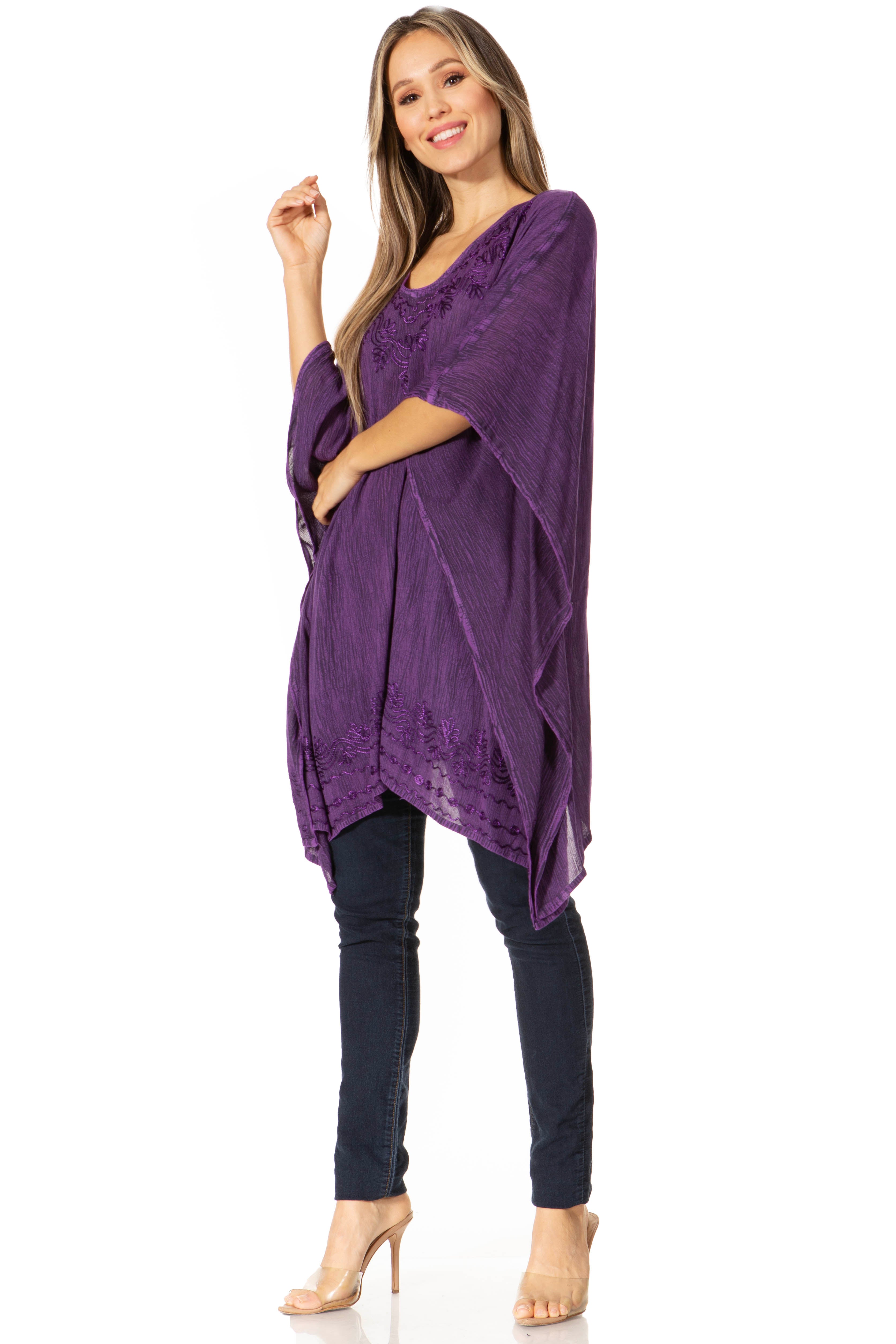 Woman wearing a purple poncho over a black top and jeans on a white background