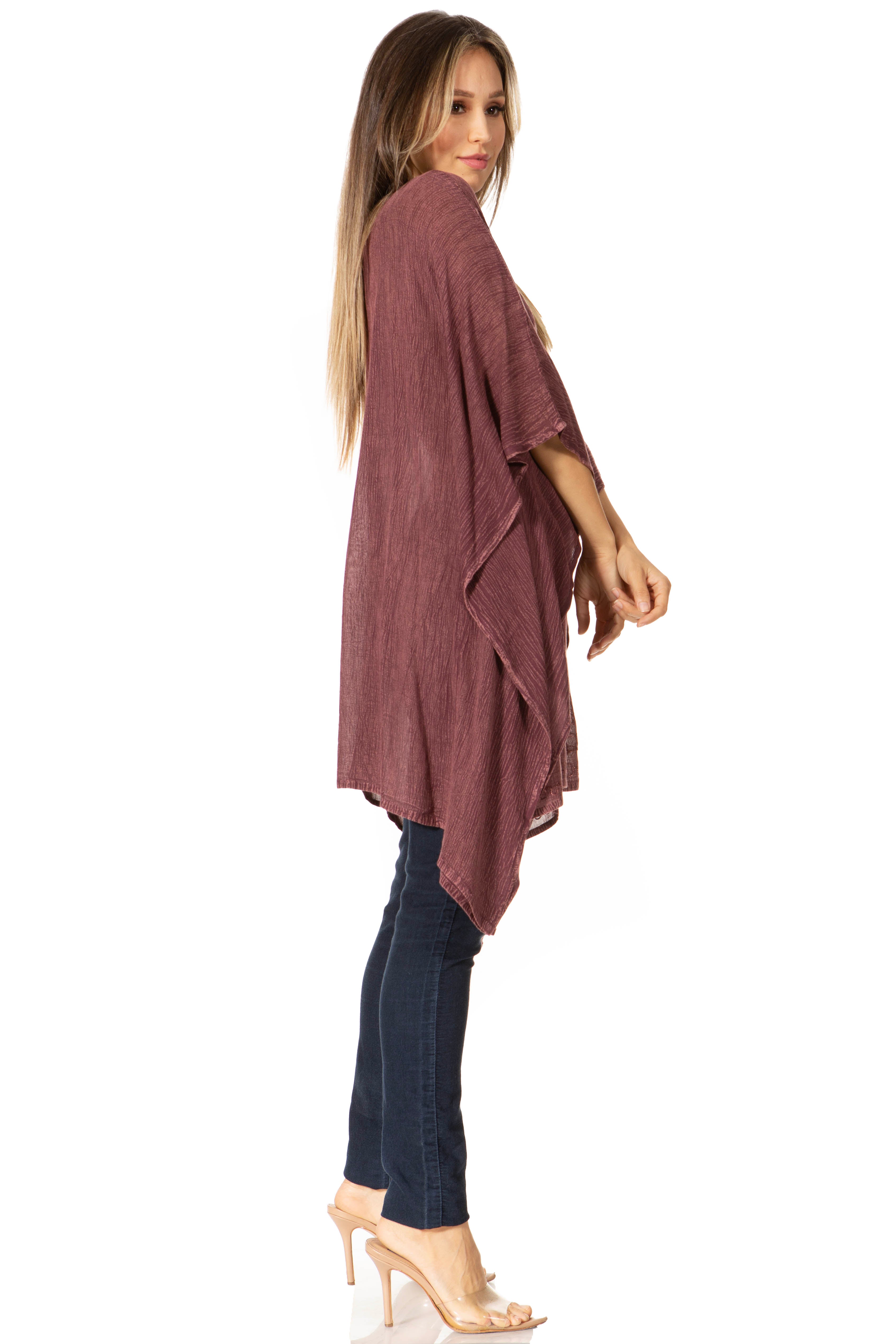 Woman wearing a mauve cardigan over a black top and jeans on a white background