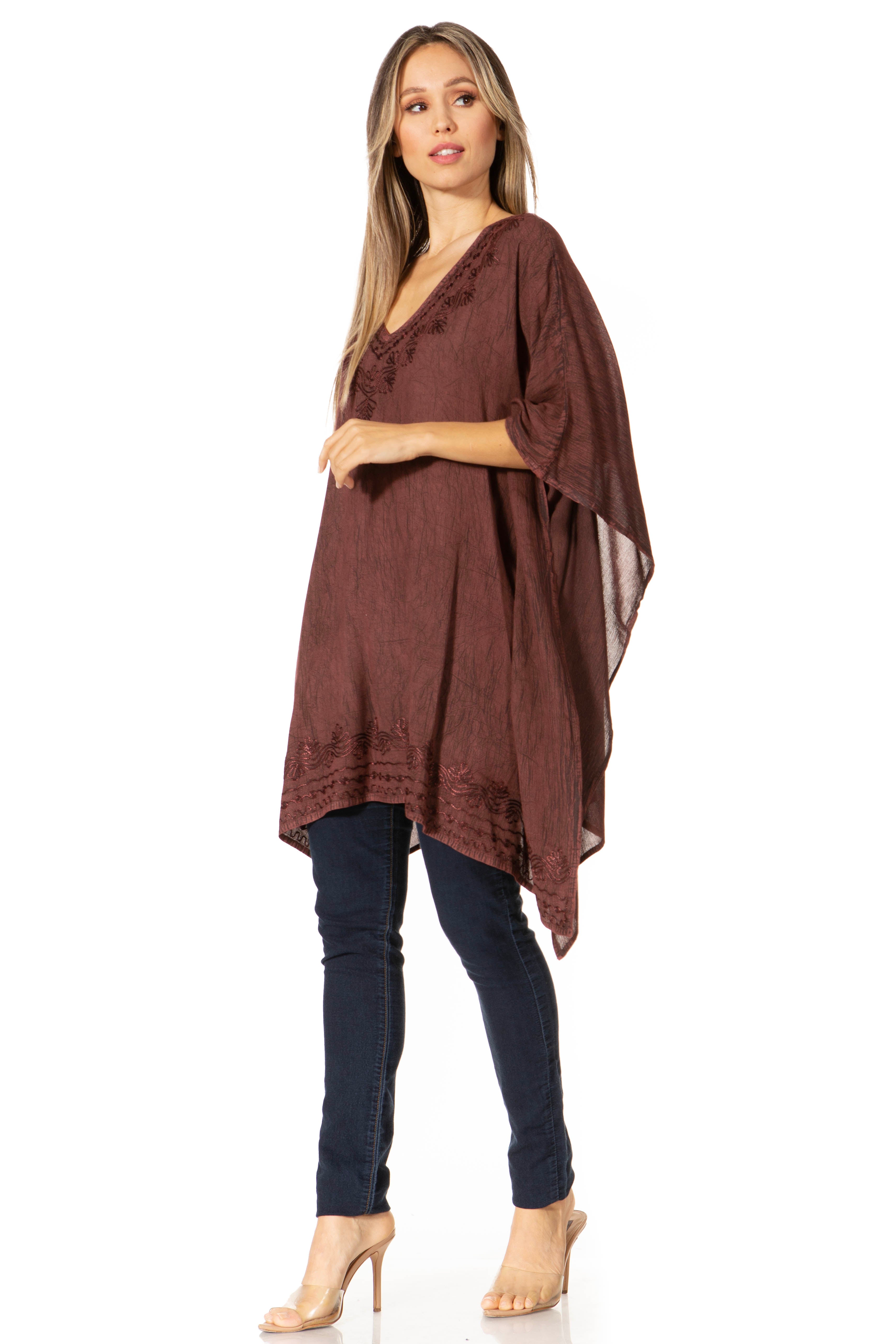 Woman wearing a brown poncho over a dark outfit on a white background