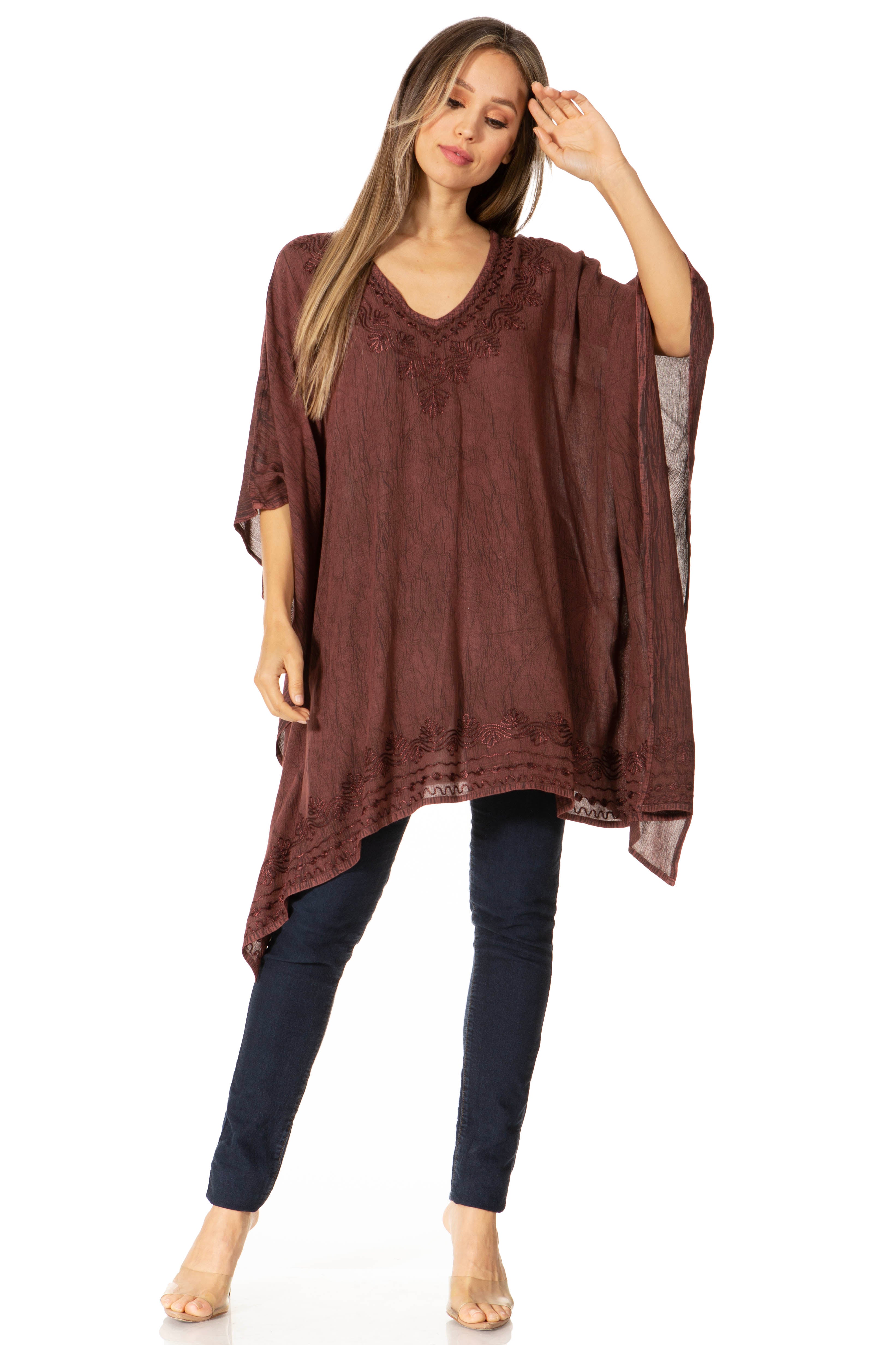 Woman wearing a brown poncho over a dark outfit on a white background