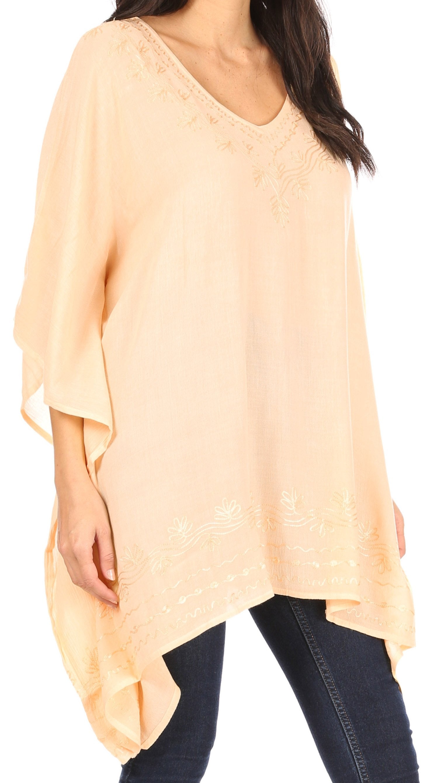 Woman wearing a light peach-colored oversized top with a plain background