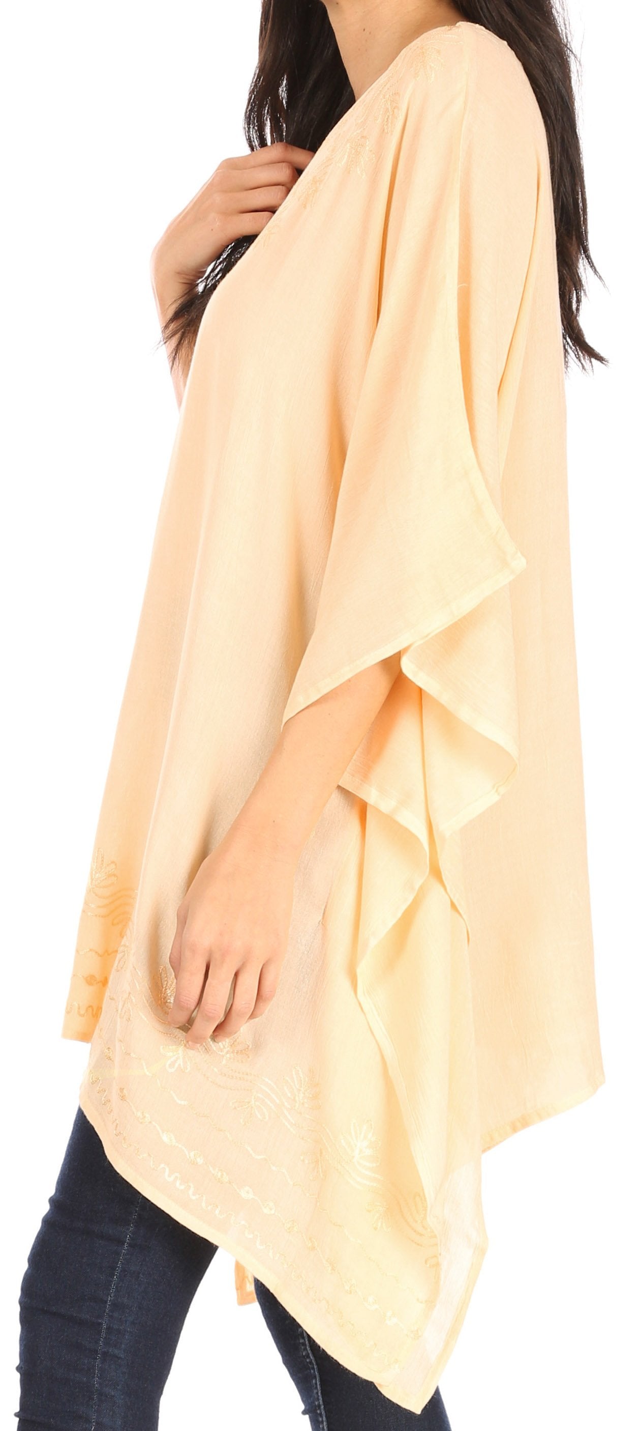 Woman wearing a light peach poncho over dark jeans on a white background