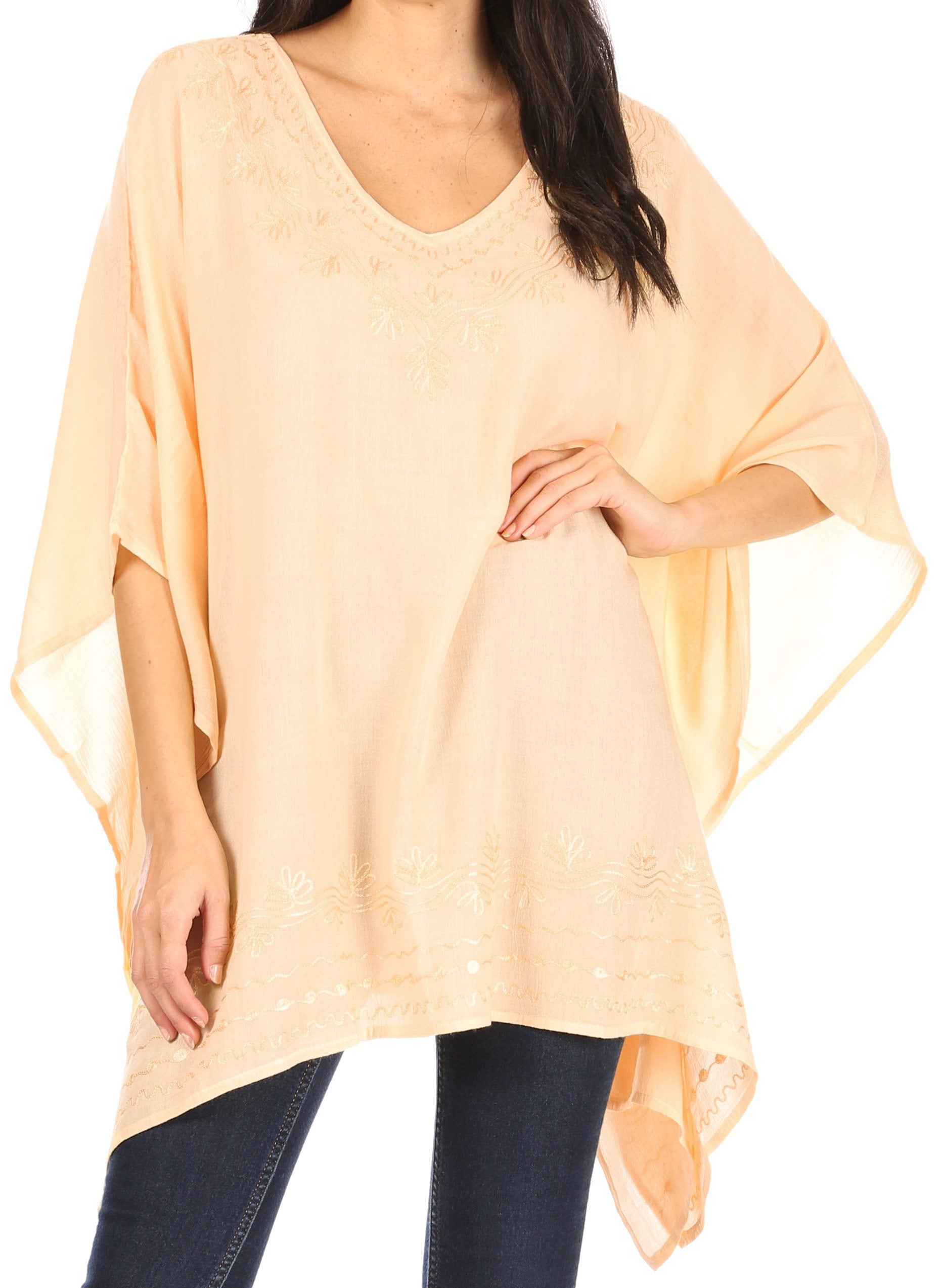 Woman wearing a light peach-colored poncho over a dark outfit