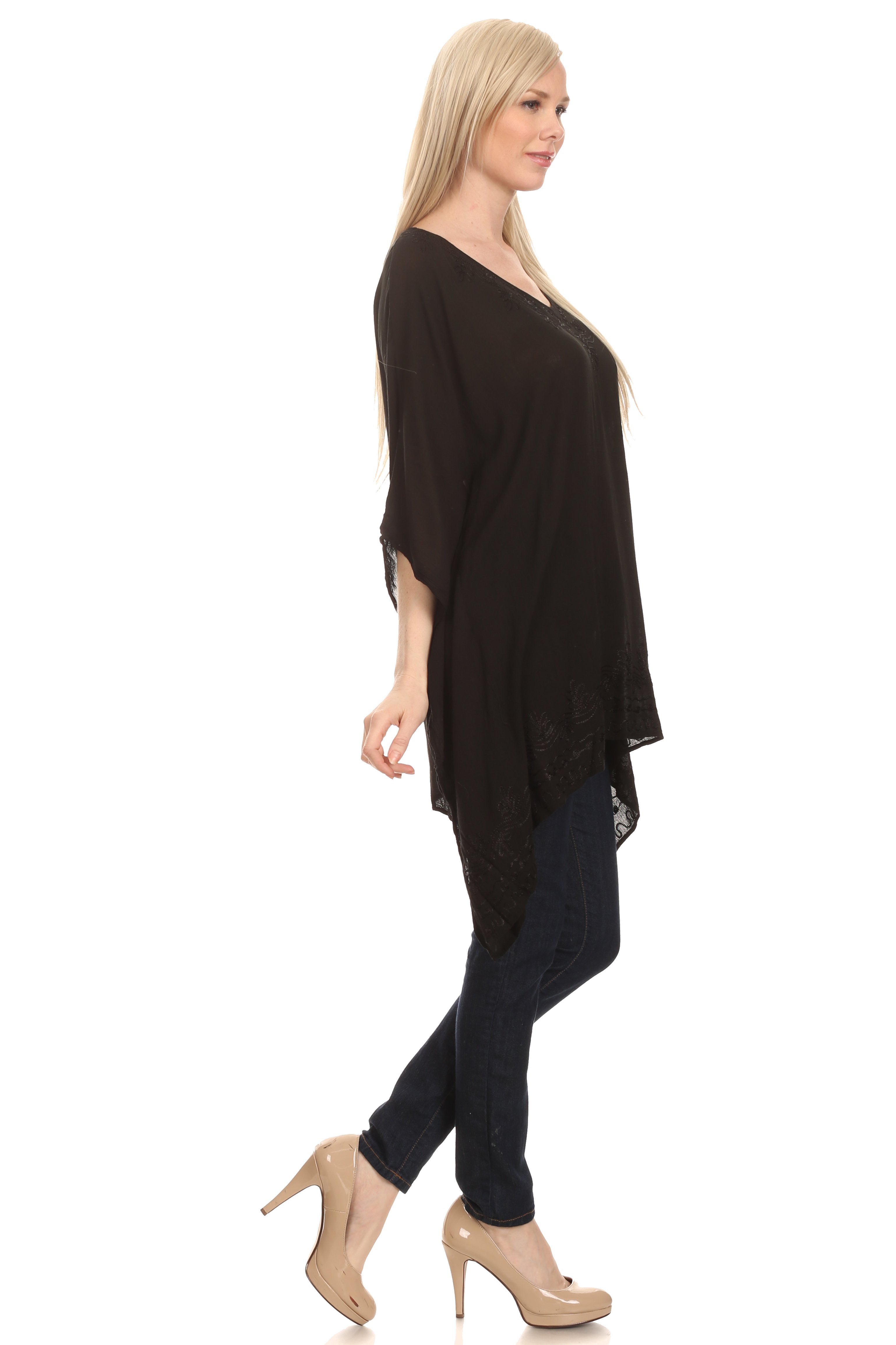 Woman wearing a black top and dark jeans on a white background
