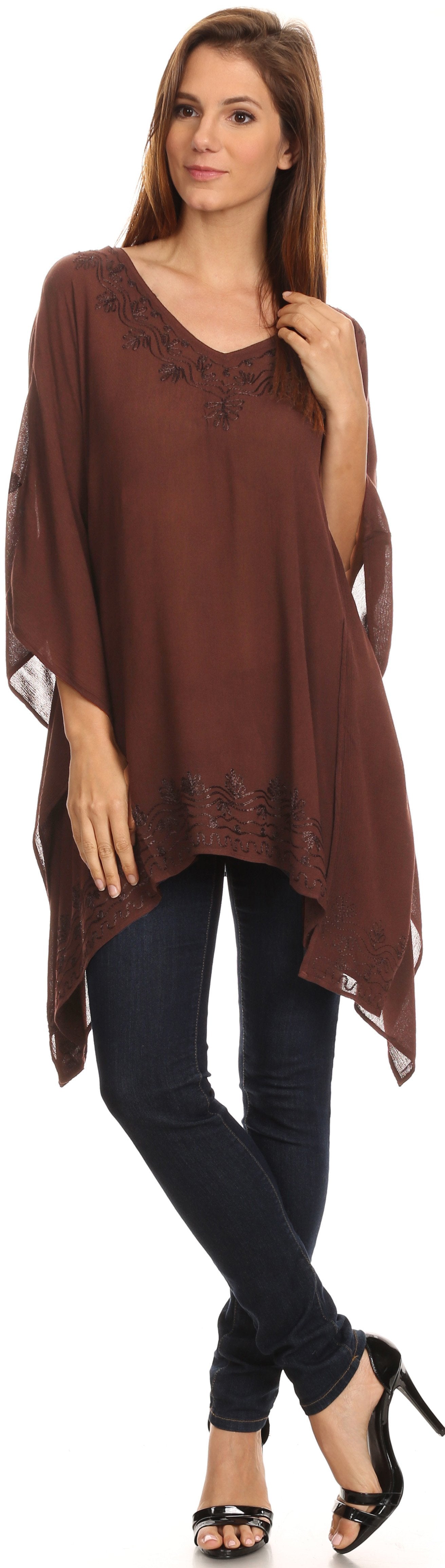 Woman wearing a brown poncho over a black top and pants on a white background