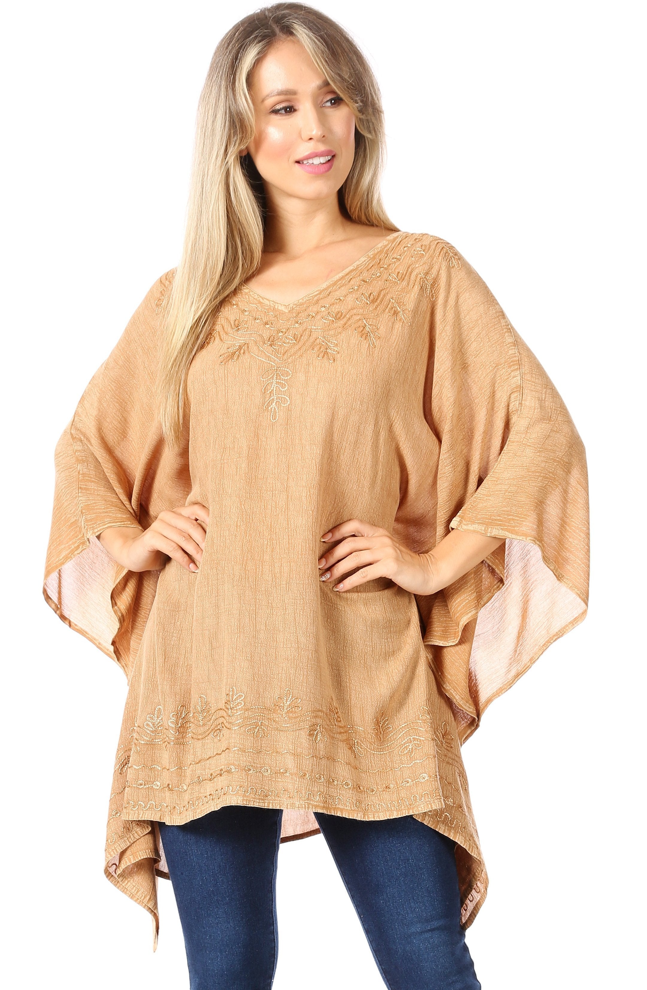 Woman wearing a beige poncho over a blue outfit on a white background