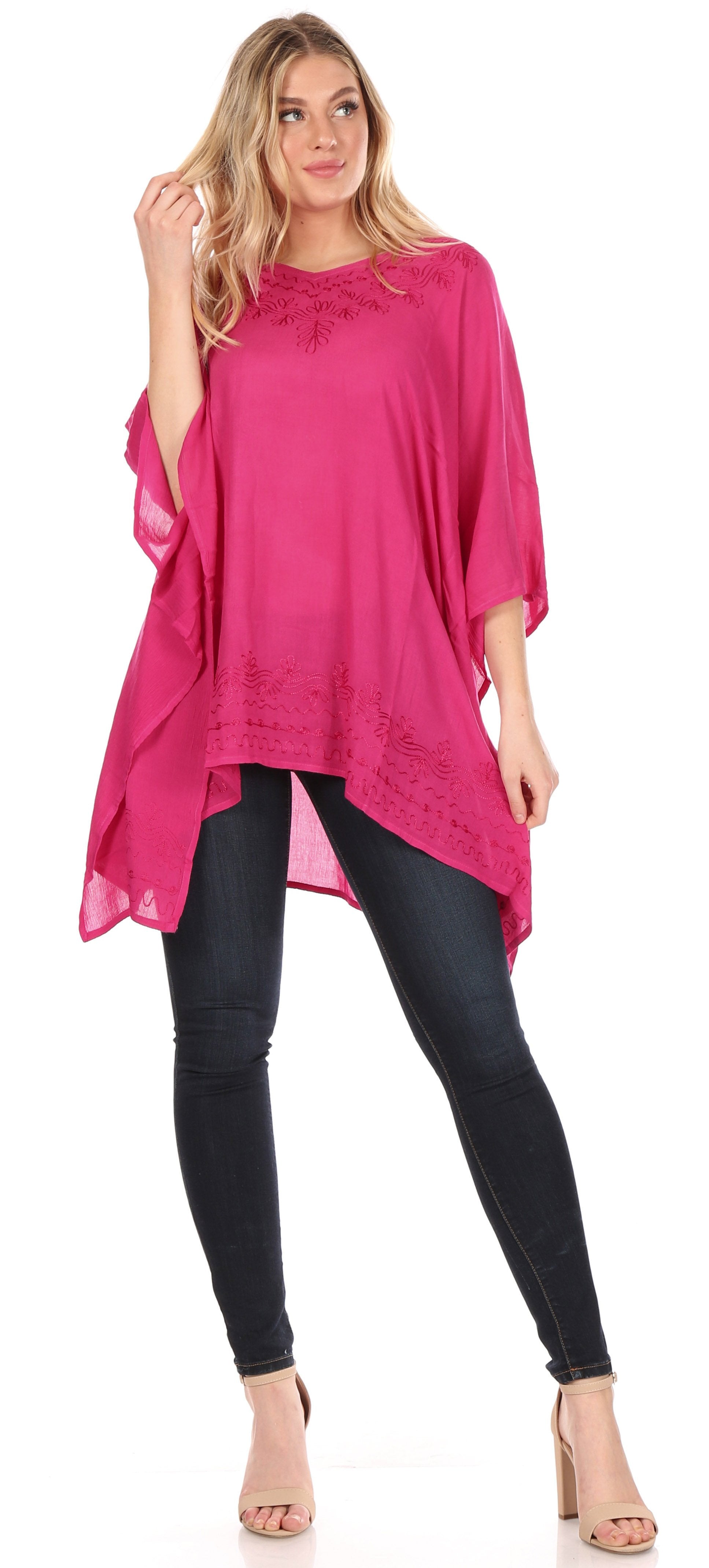 Woman wearing a bright pink poncho over a black outfit on a white background