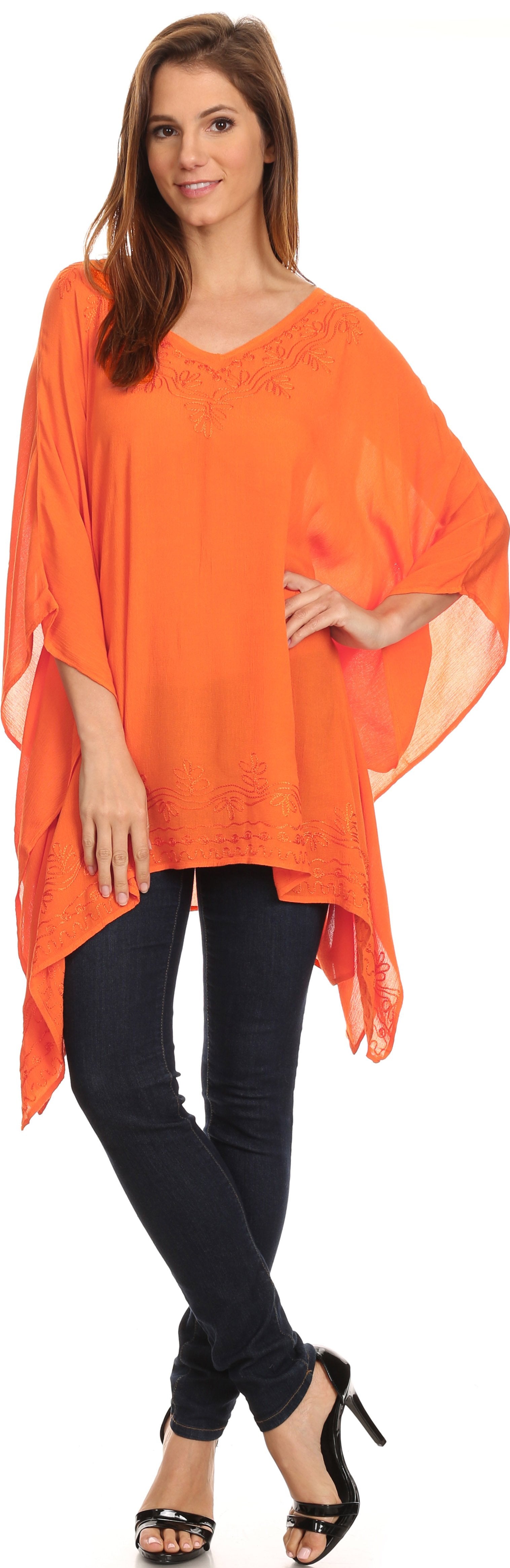 Woman wearing an orange poncho over a black top and pants on a white background