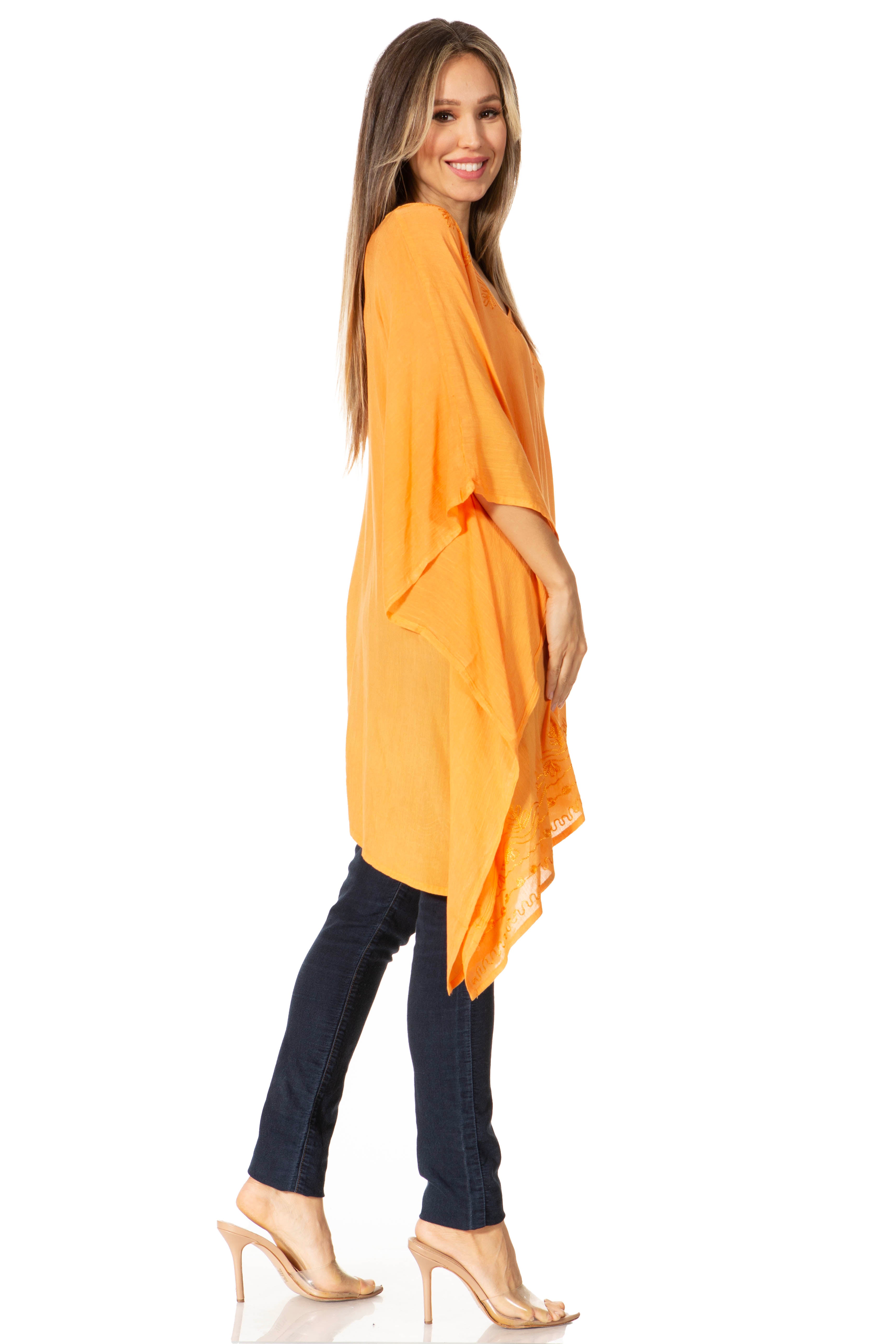 Woman wearing an orange poncho over a black top and jeans on a white background