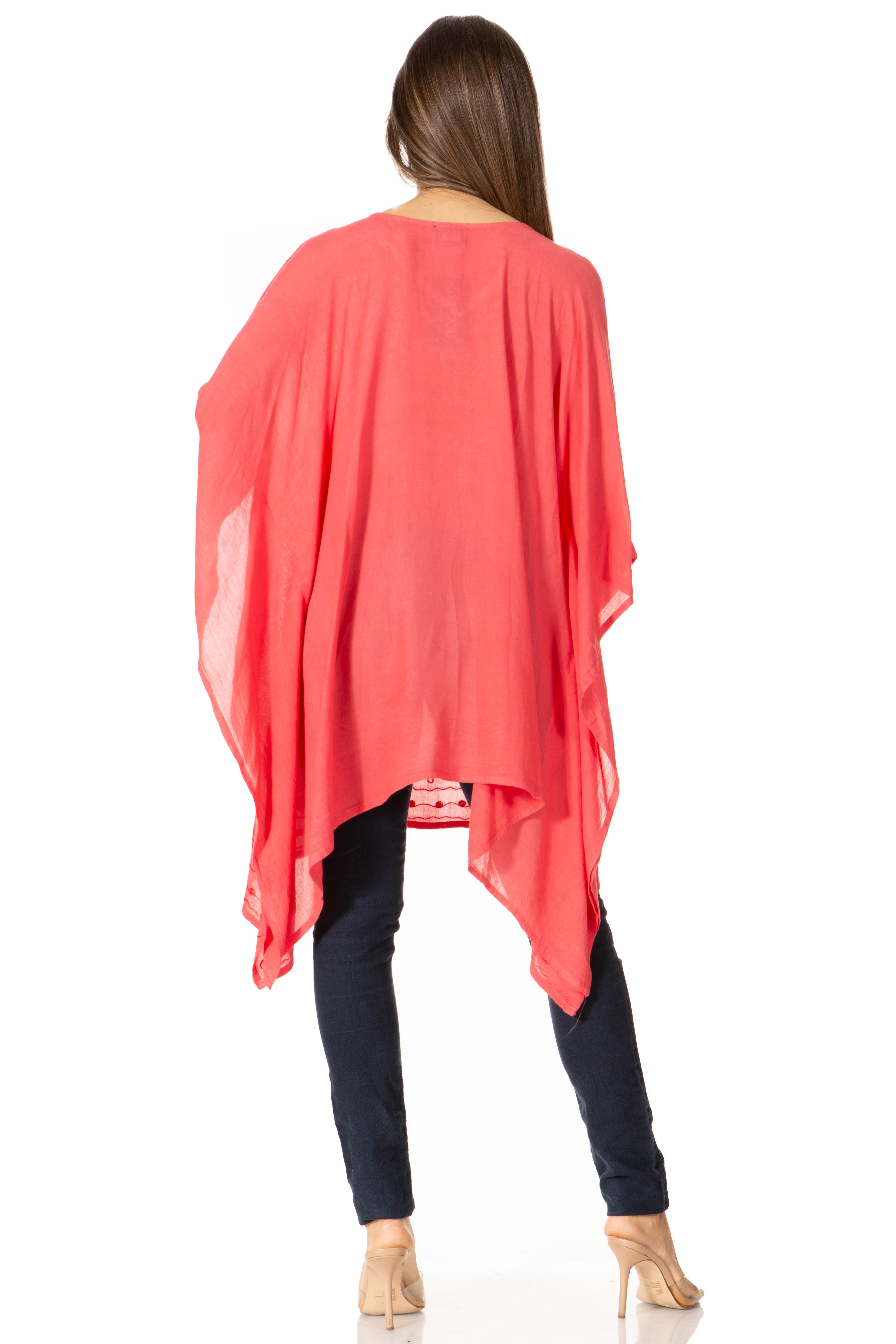 Woman wearing a coral poncho over a black outfit on a white background