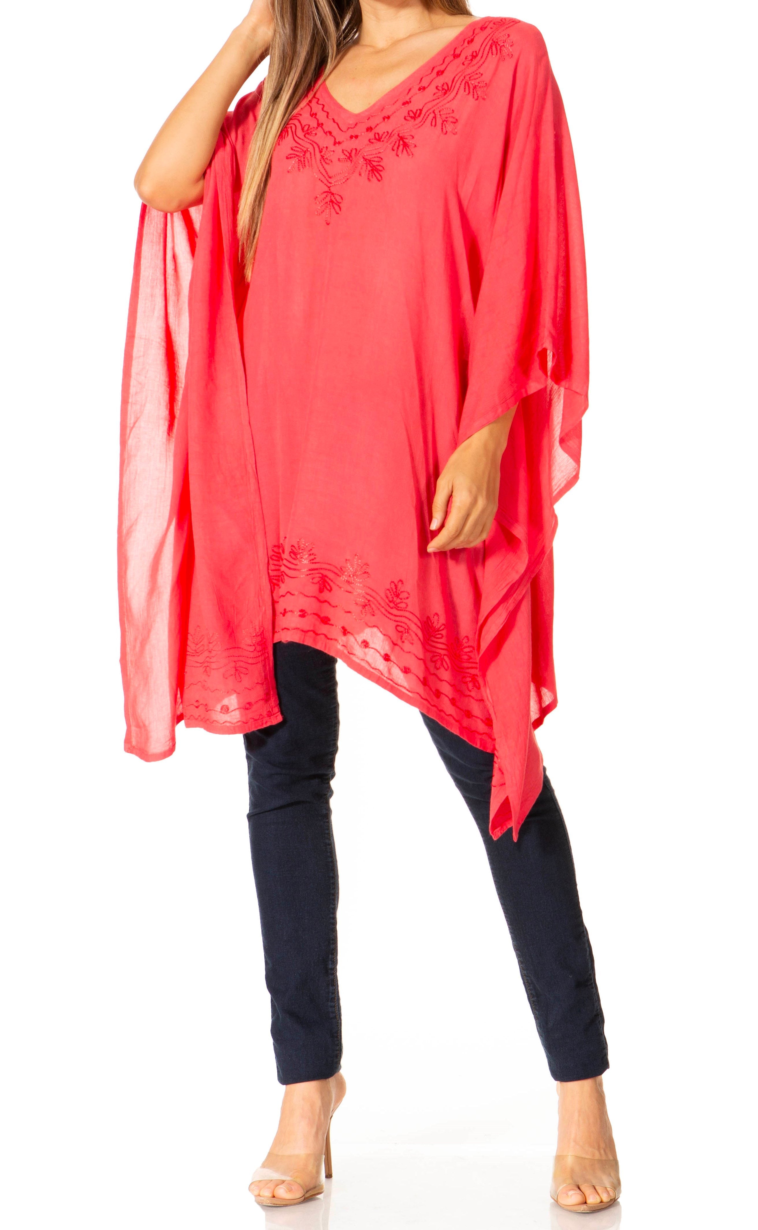 Woman wearing a coral poncho over a black outfit on a white background