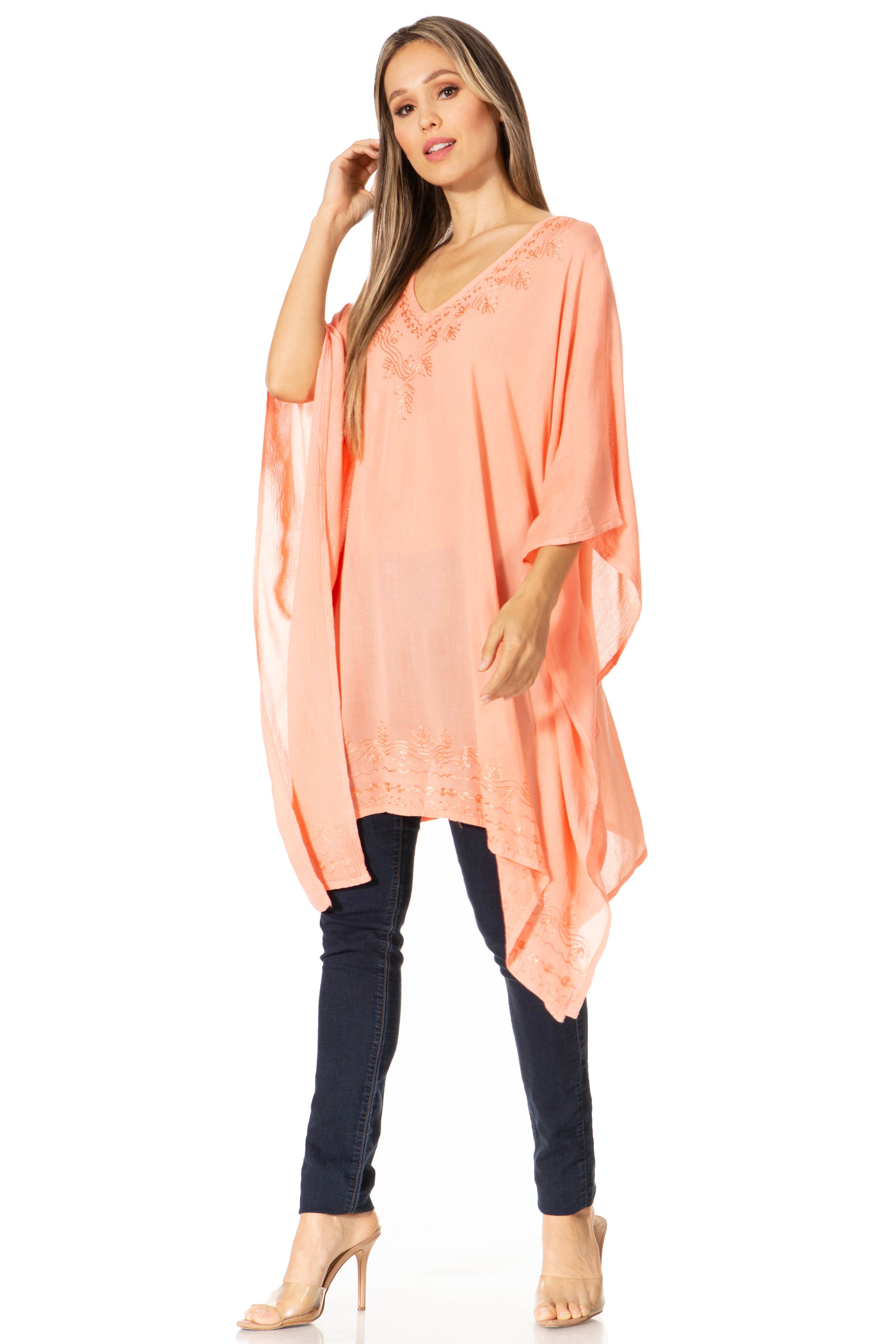 Woman wearing a peach-colored long top and dark pants on a white background