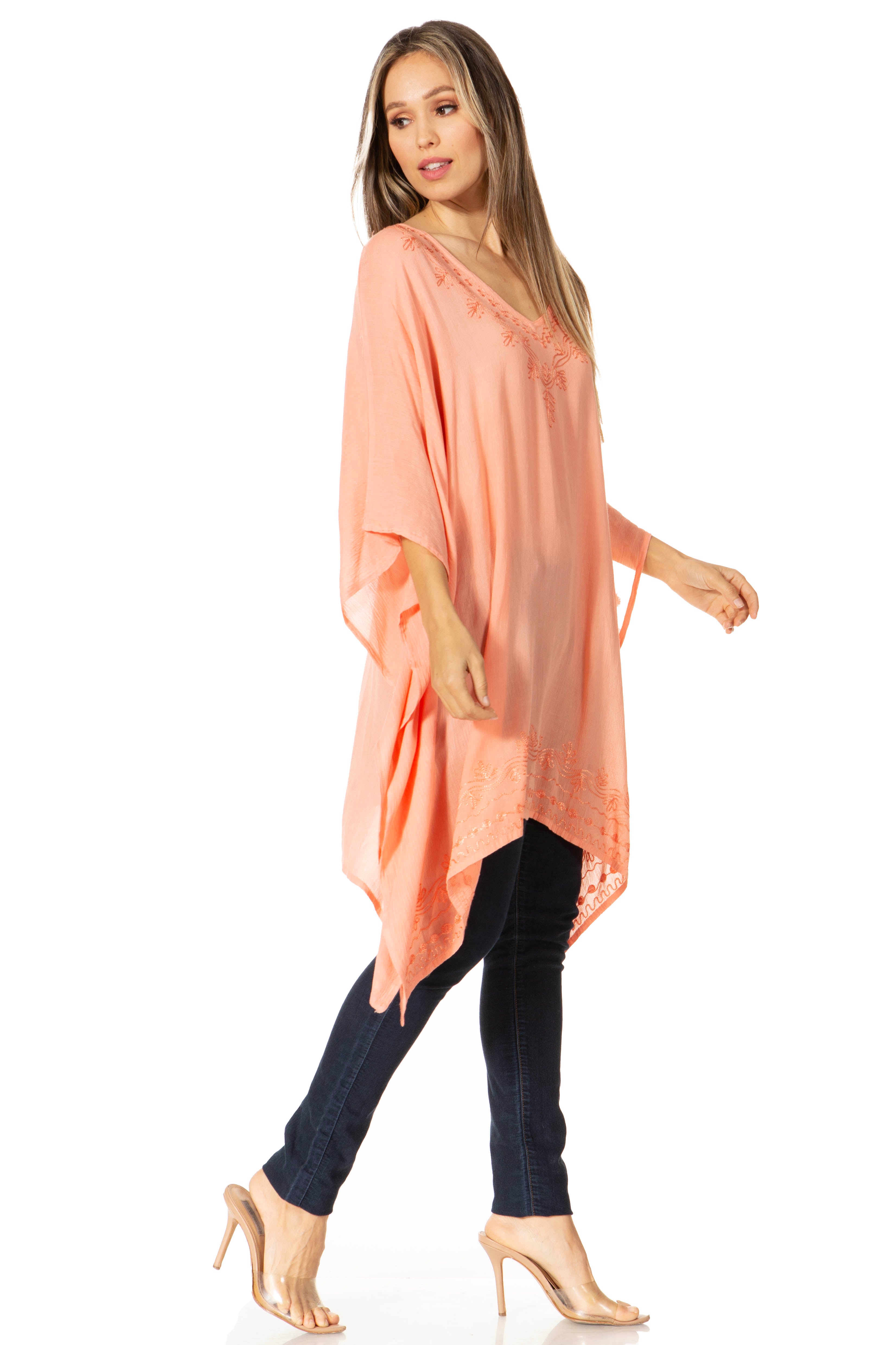 Woman wearing a peach-colored poncho over a black outfit on a white background