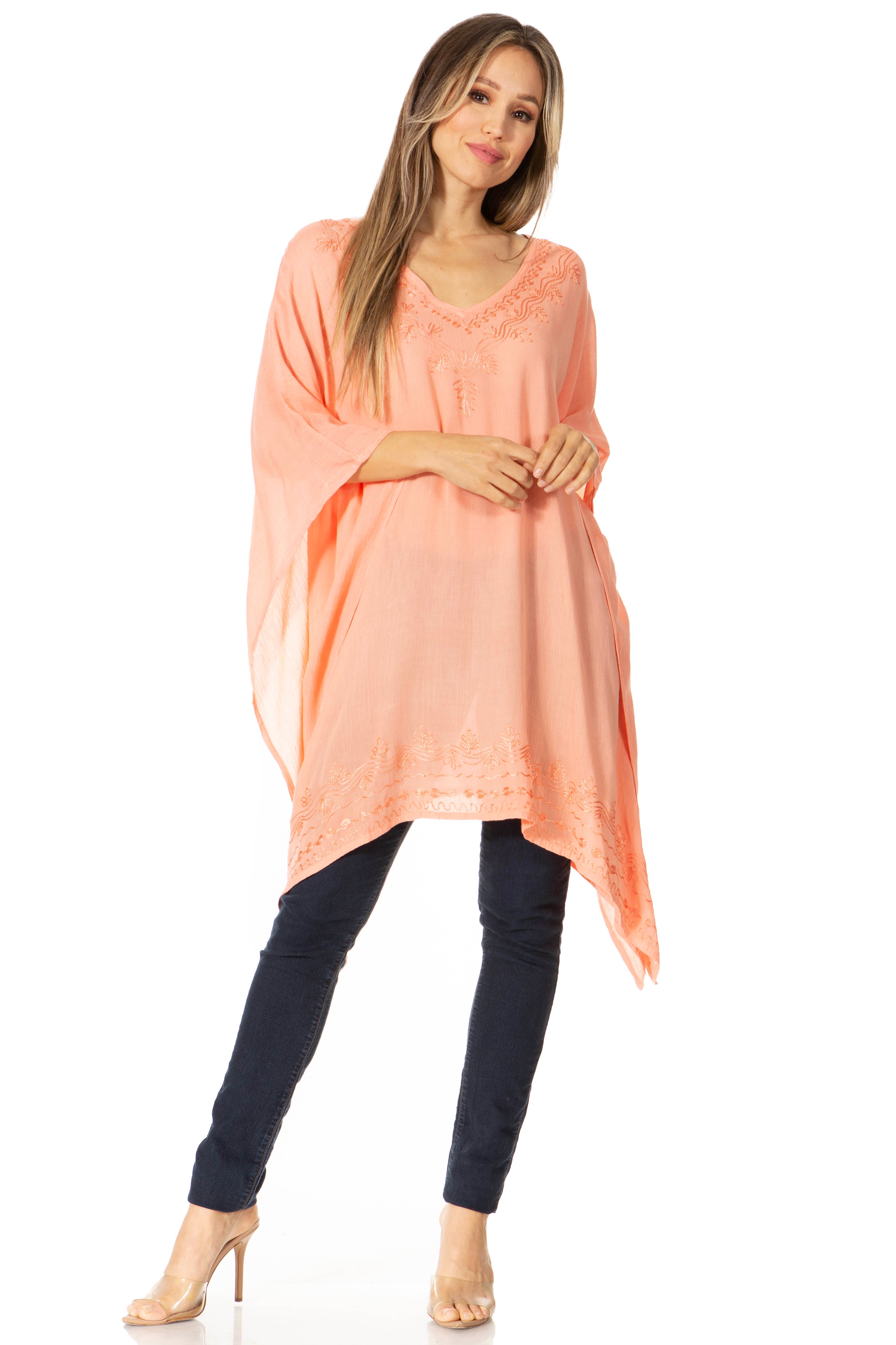 Woman wearing a peach-colored tunic and dark pants on a white background