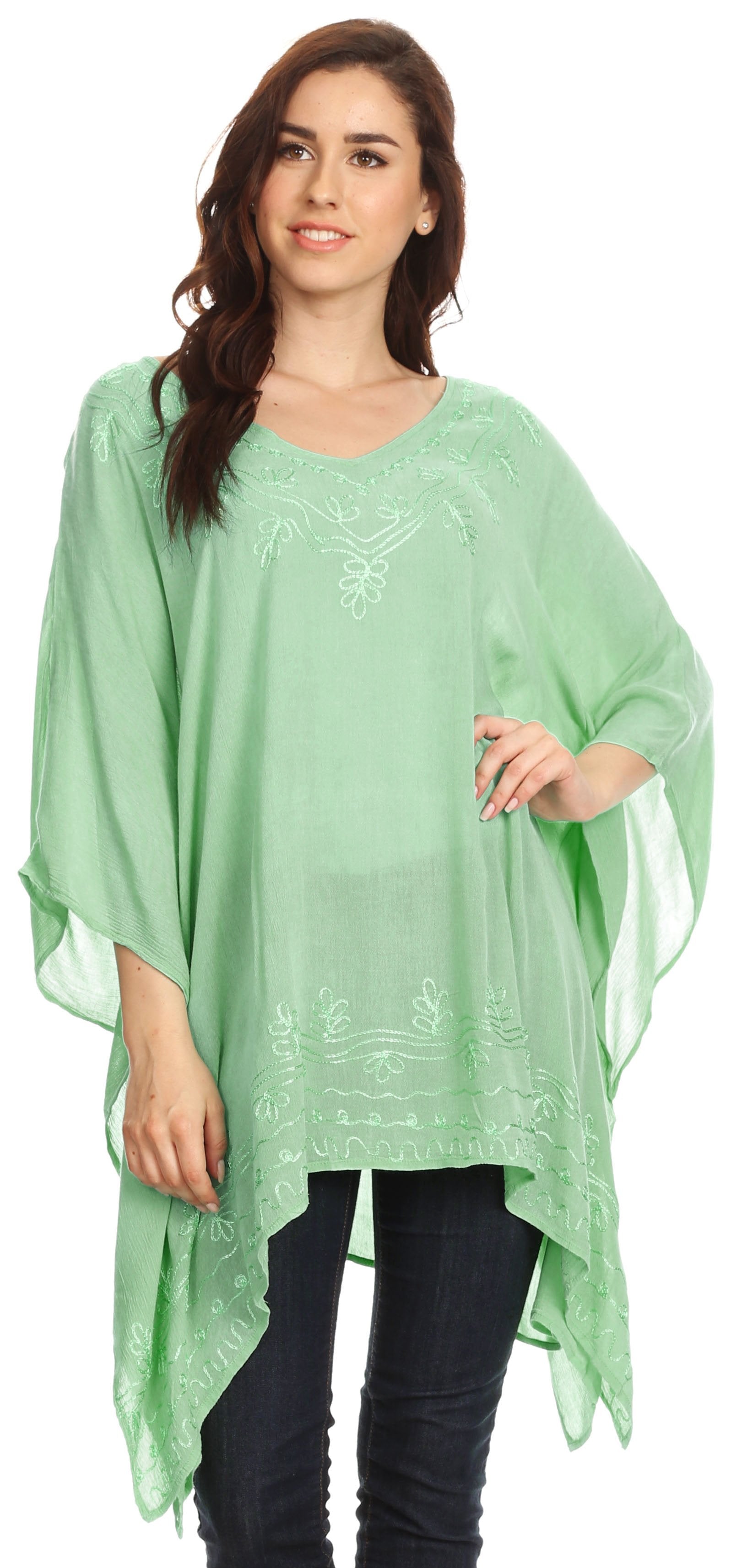 Woman wearing a light green poncho with embroidery on a white background