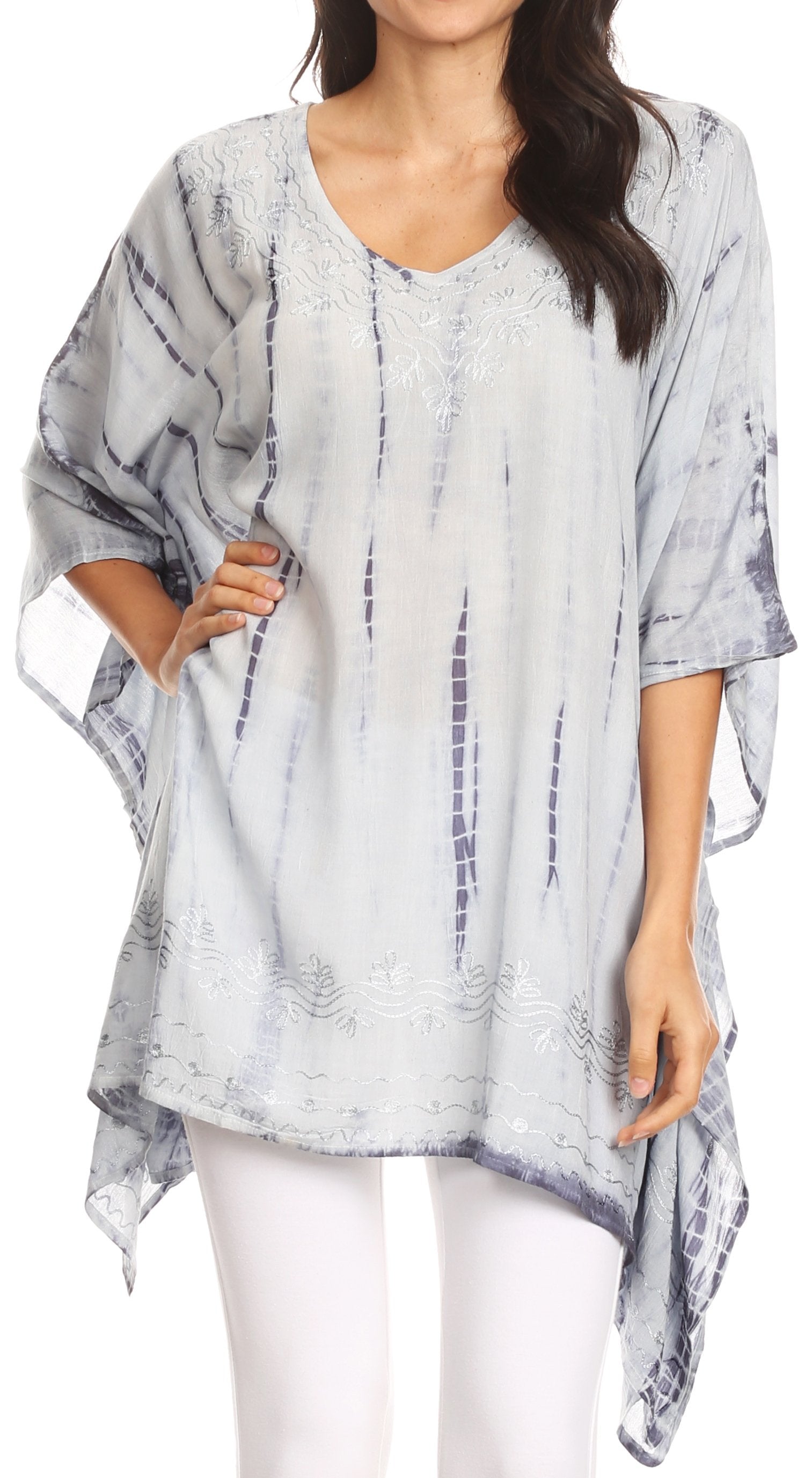 Woman wearing a light gray and white patterned poncho over a white top and pants on a white background