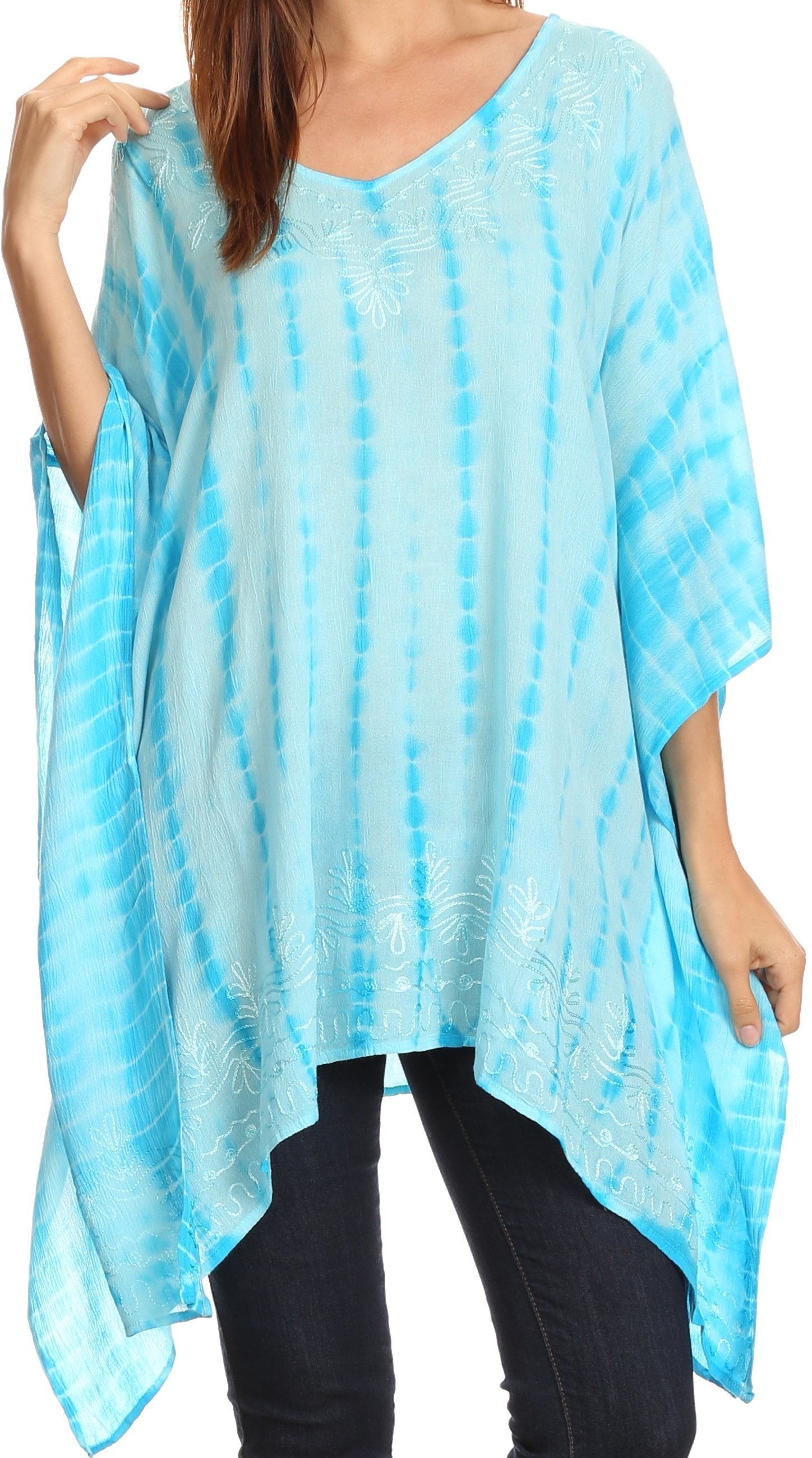 Woman wearing a light blue tie-dye poncho over dark pants on a white background