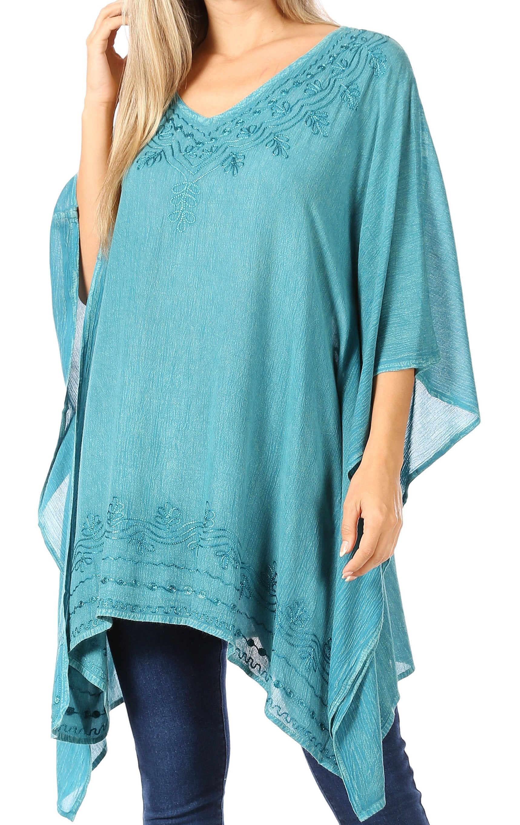 Teal poncho with lace details worn by a person on a white background