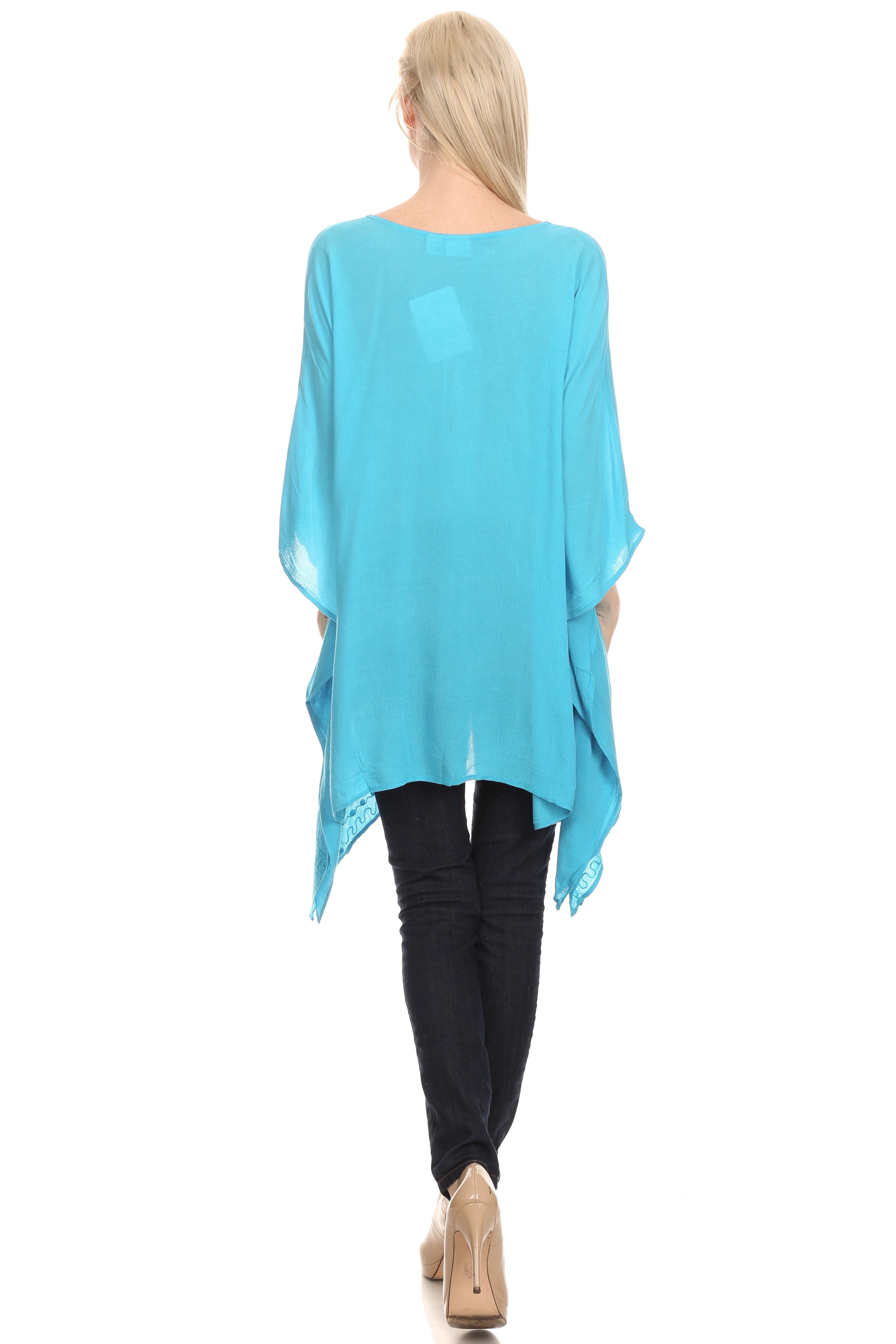 Woman wearing a turquoise poncho over a black outfit on a white background