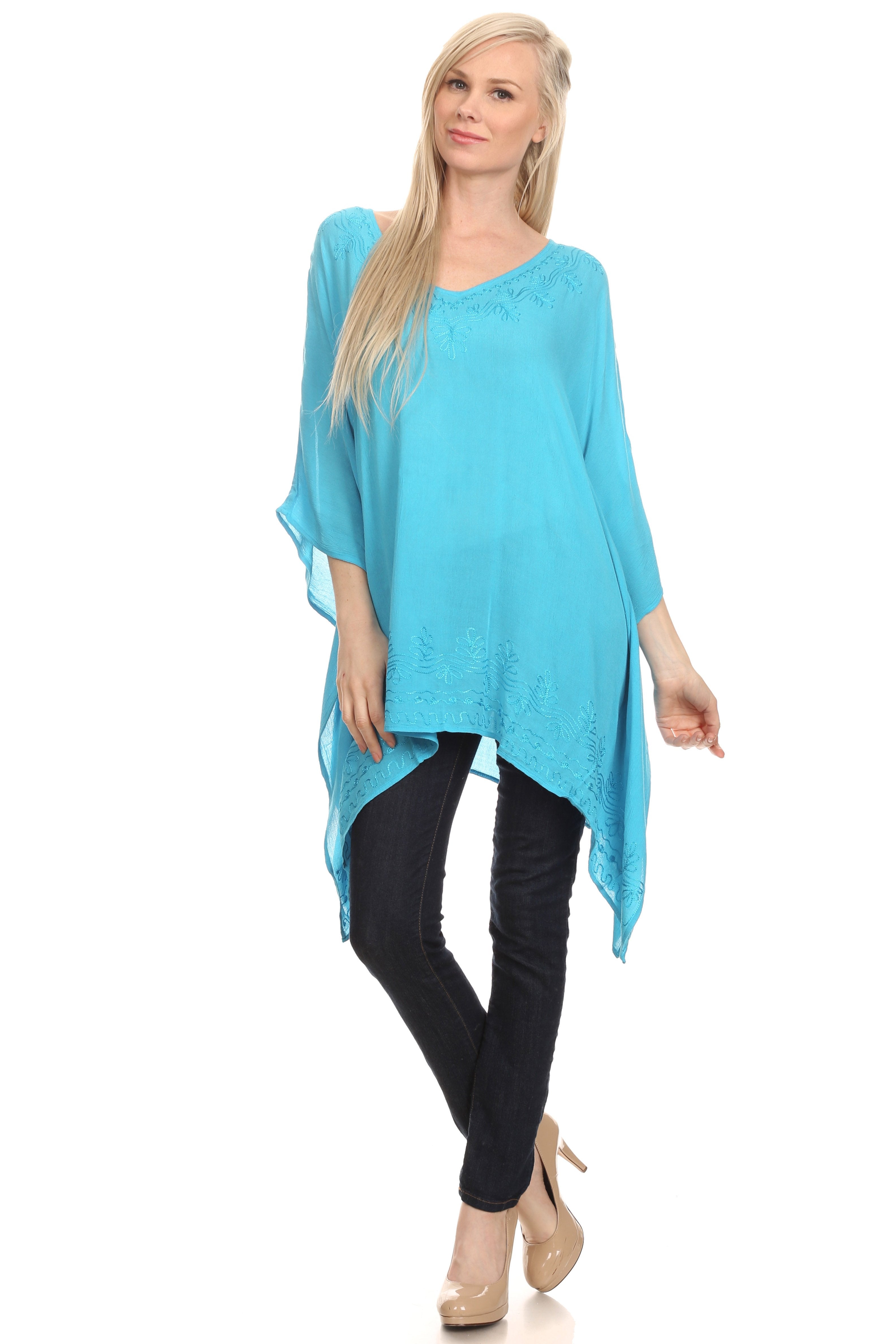 Woman wearing a turquoise poncho over a black outfit on a white background