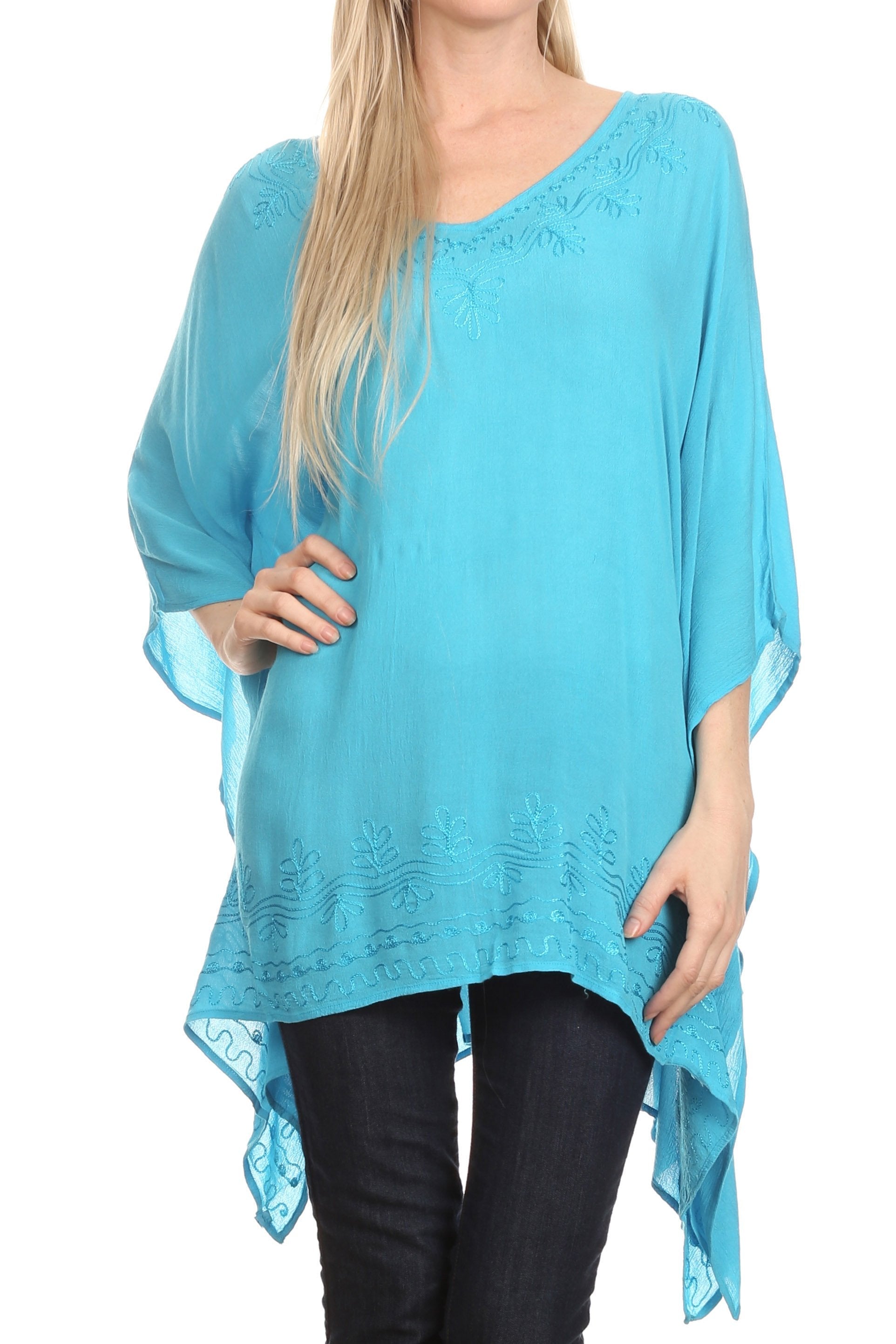 Woman wearing a turquoise poncho with lace details on a white background