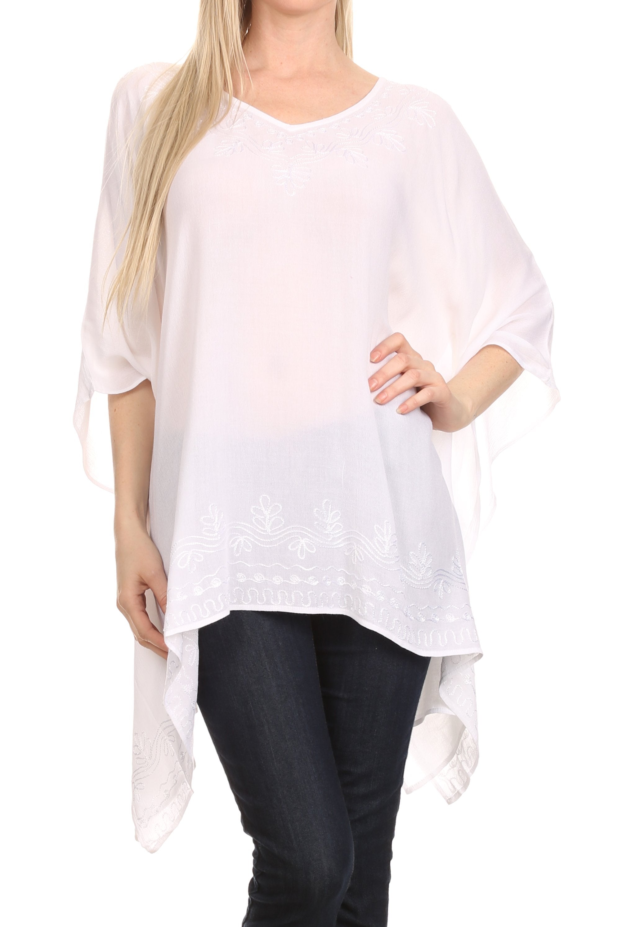 Woman wearing a white poncho over a black outfit on a white background