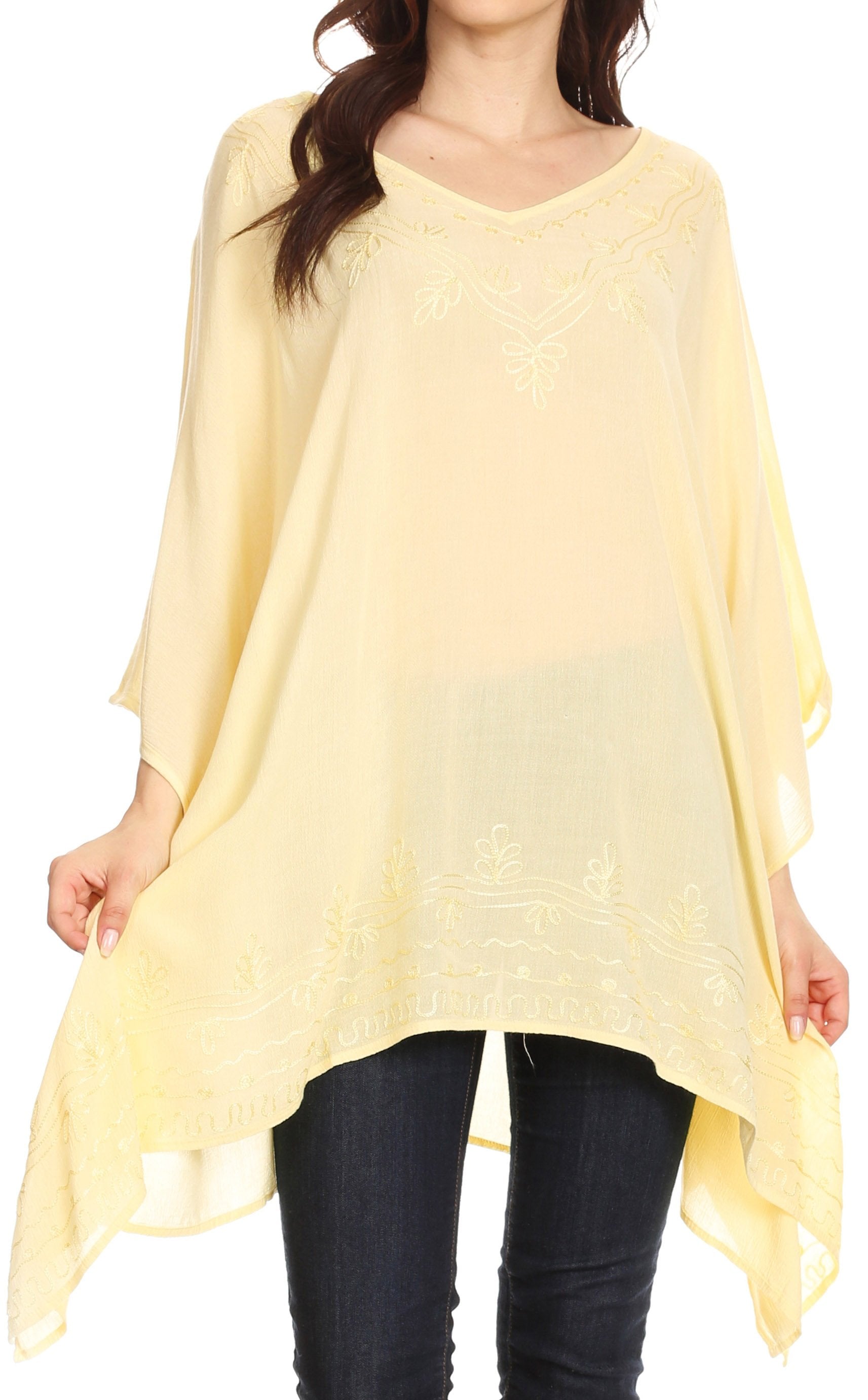 Woman wearing a light yellow poncho over dark pants on a white background