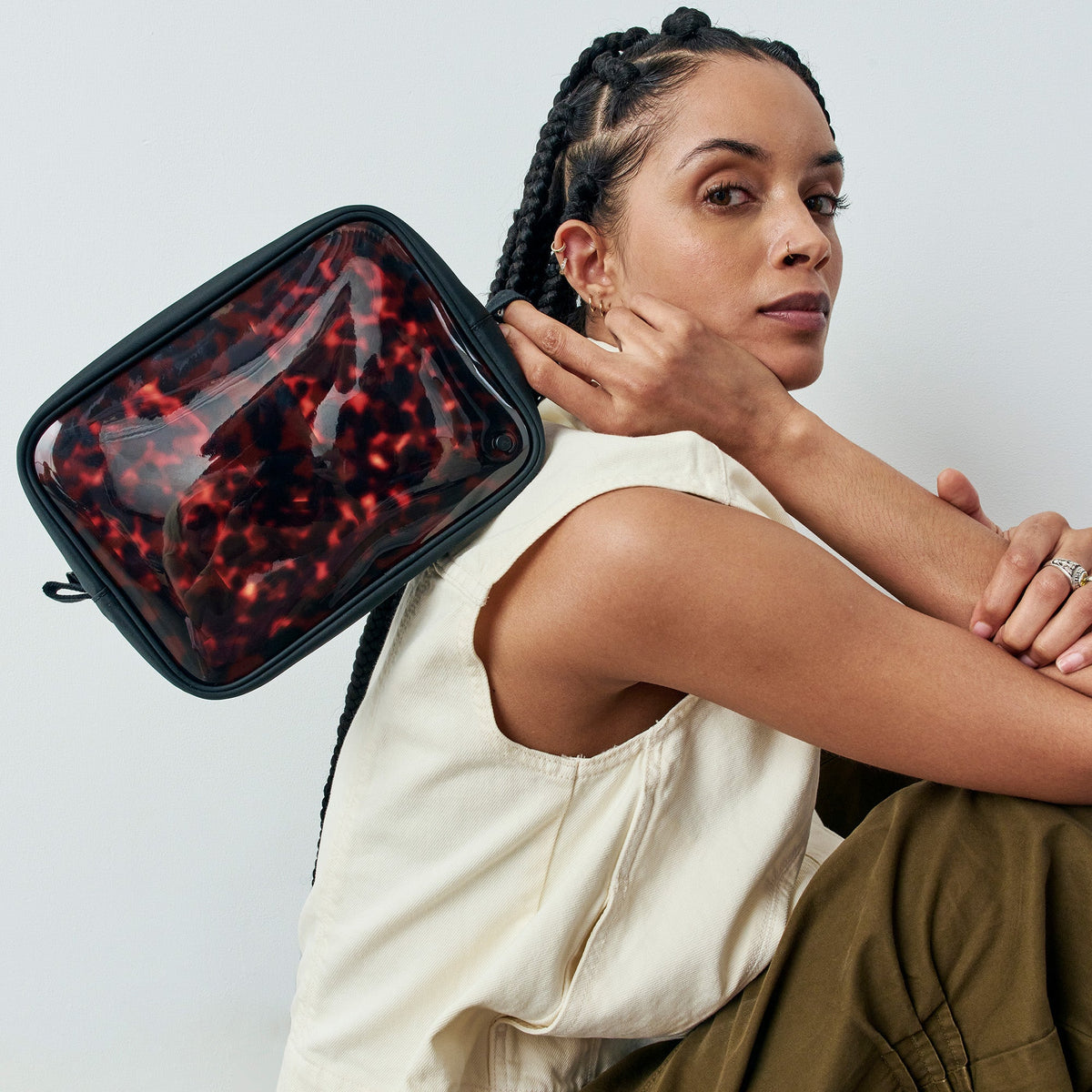 Woman holding a red and black patterned pouch against a white background