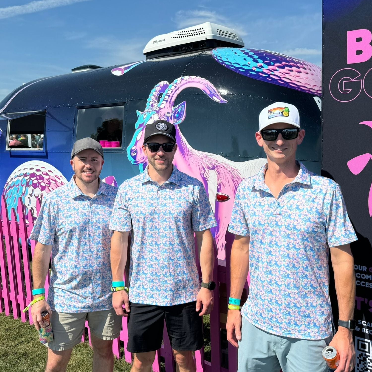 Three men in matching outfits standing in front of a colorful trailer with a dragon design.