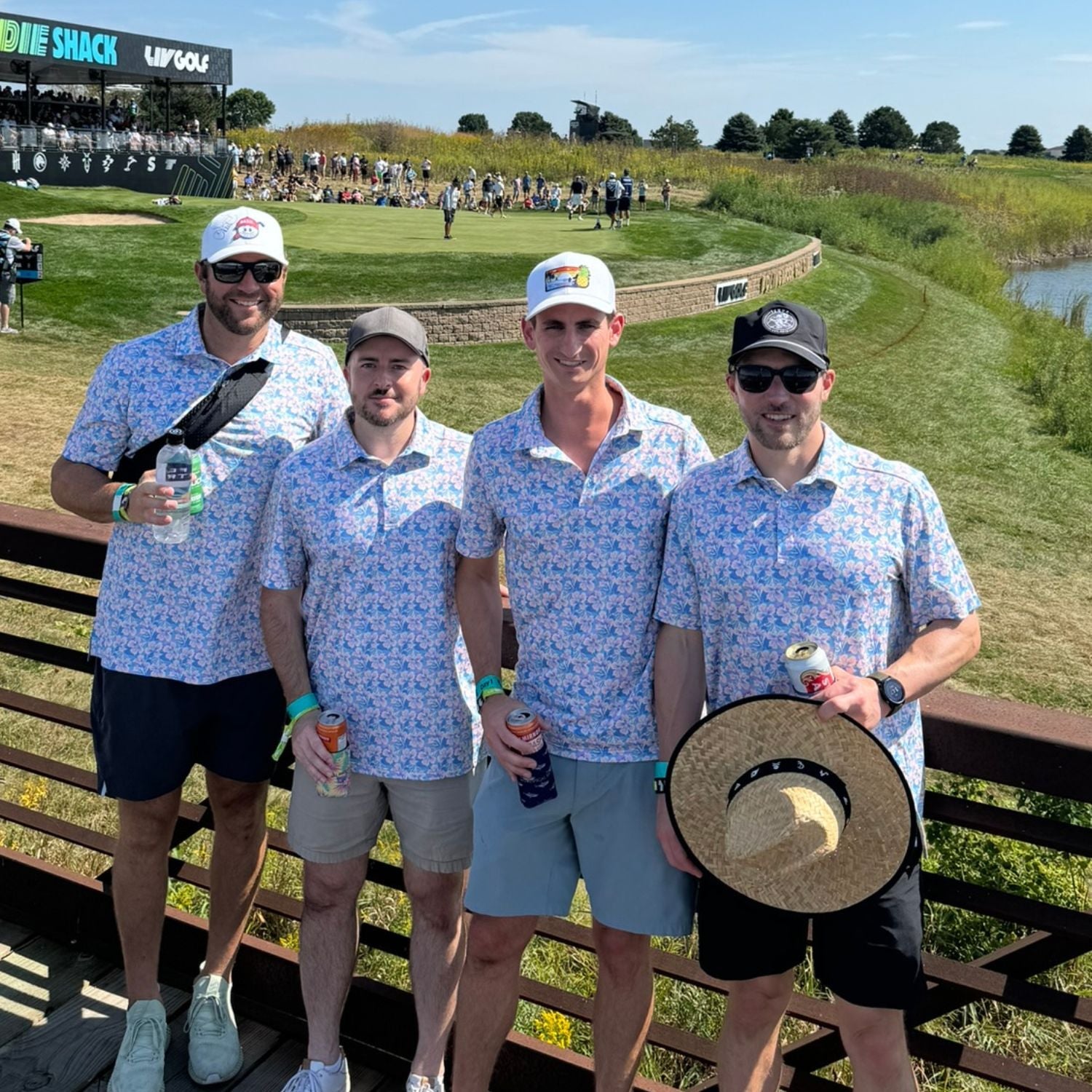 Four men in matching outfits standing on a golf course with a green and blue sky.