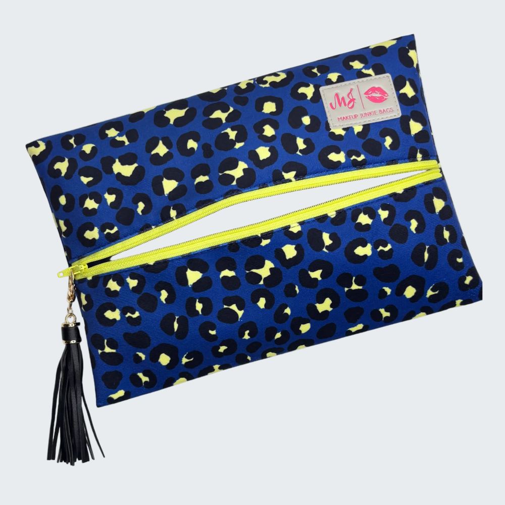 Blue clutch with yellow leopard print pattern and black tassel on a white background