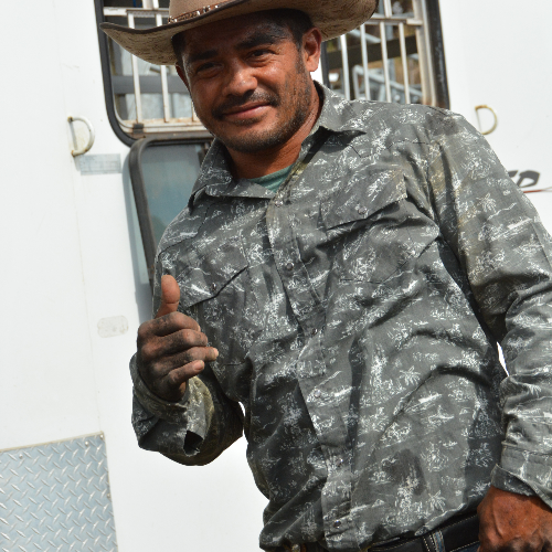 Man in camouflage uniform giving a thumbs-up in front of a vehicle