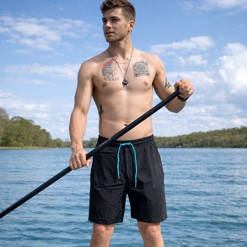 Man holding a paddle on a lake with trees and blue sky in the background