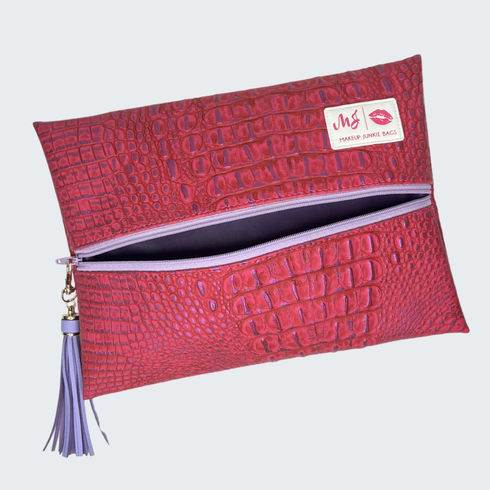Red textured makeup bag with a purple tassel on a white background